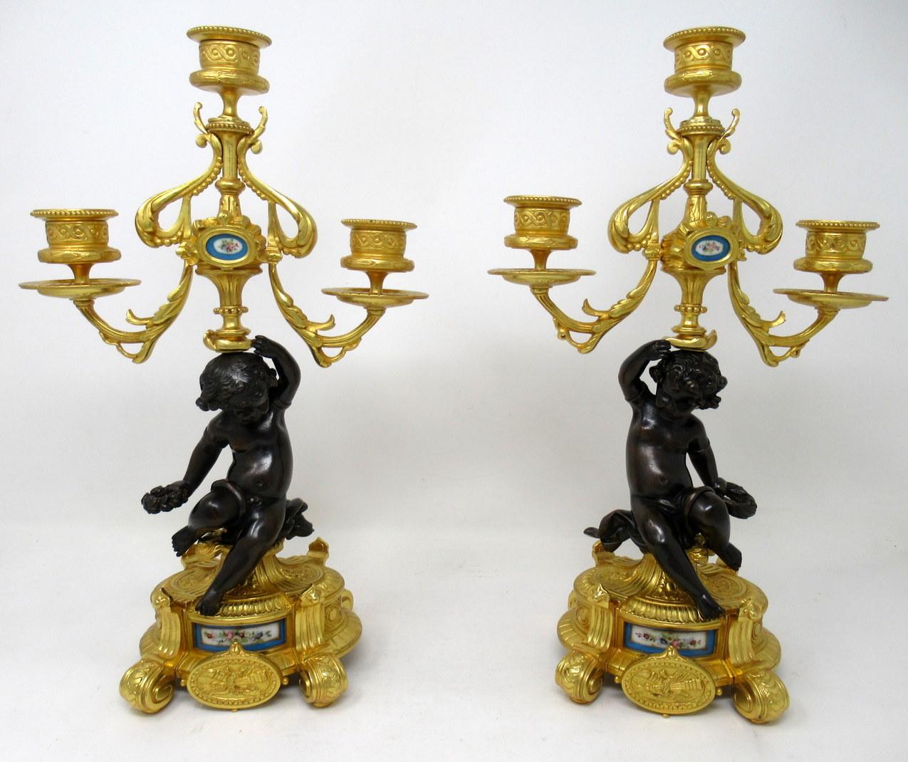 A fine pair of stylish and imposing French ormolu and patinated bronze three-light table or mantle candelabra of outstanding quality, mid-late 19th century. 

Each with a central seated patinated solid bronze Cherub holding a loft on one hand a