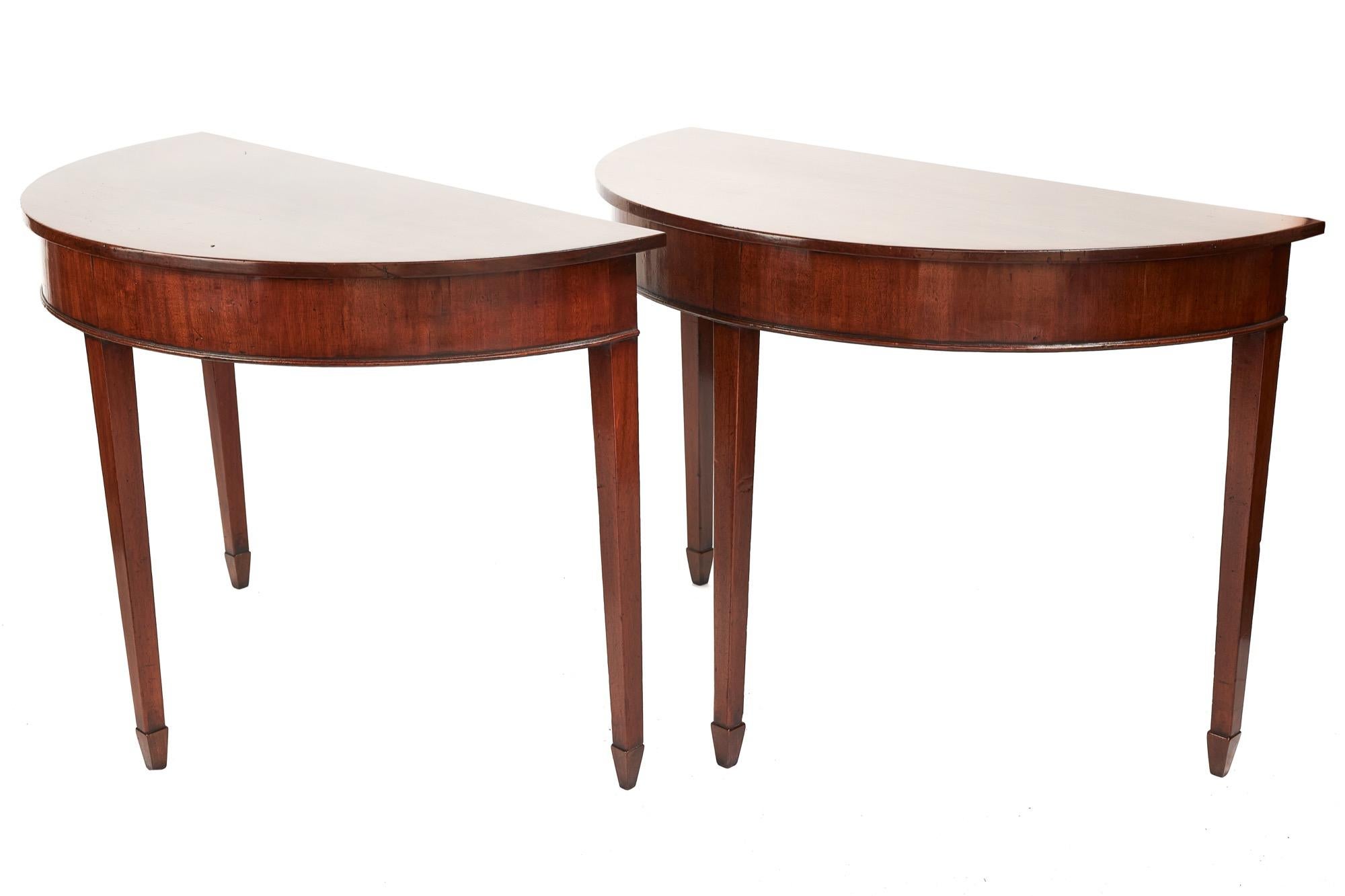 Antique pair of George III demilune mahogany console tables having very appealing mahogany tops each with three attractive mahogany tapering legs and terminating in spade feet.

A lovely Classic pair of the period in wonderful original condition.
