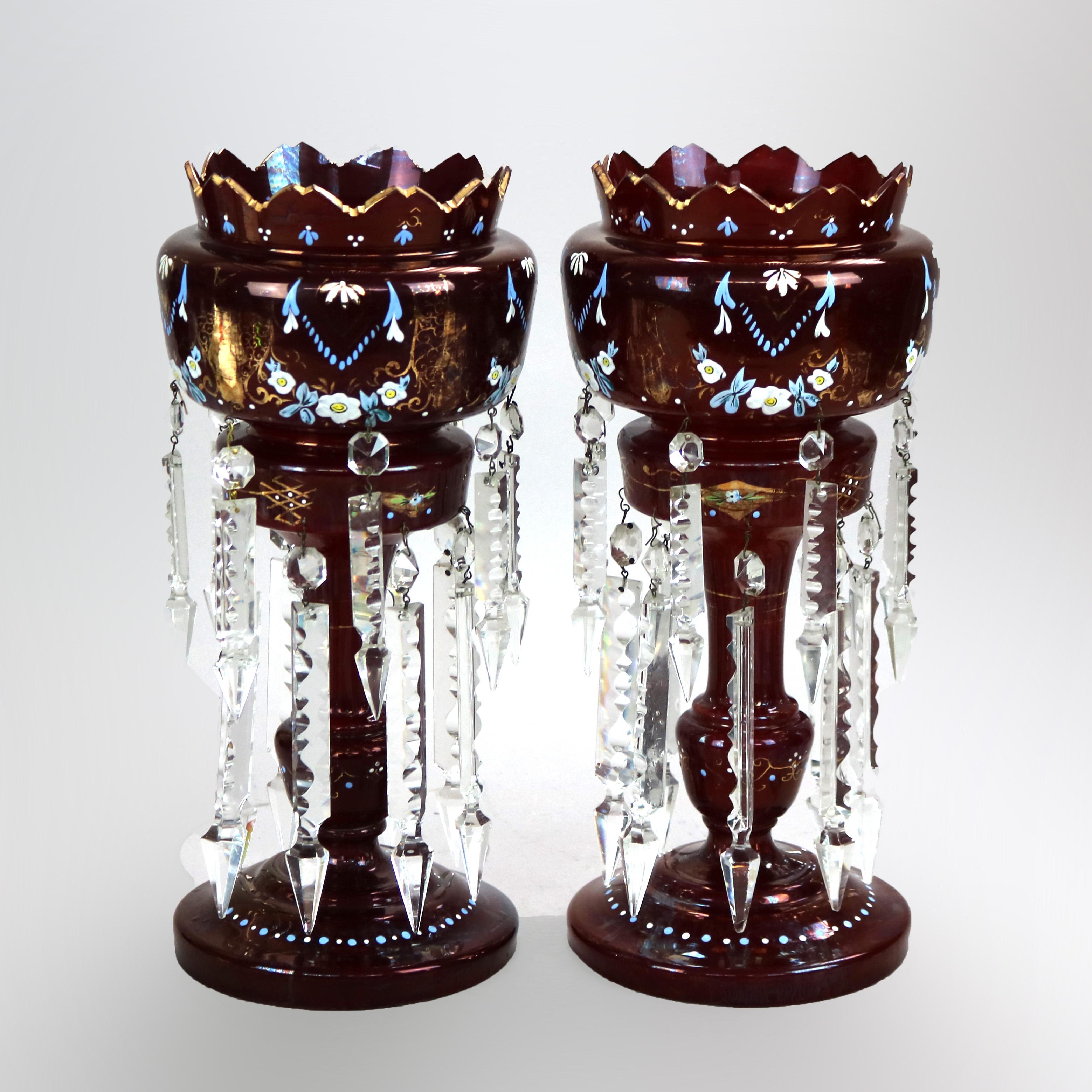 An antique pair of mantel lusters offer cranberry glass construction in urn form with serrated rim, hand painted floral decoration, gilt highlights and hanging cut prisms throughout, c1890

Measures - 14.25''H x 6''W x 6''D.