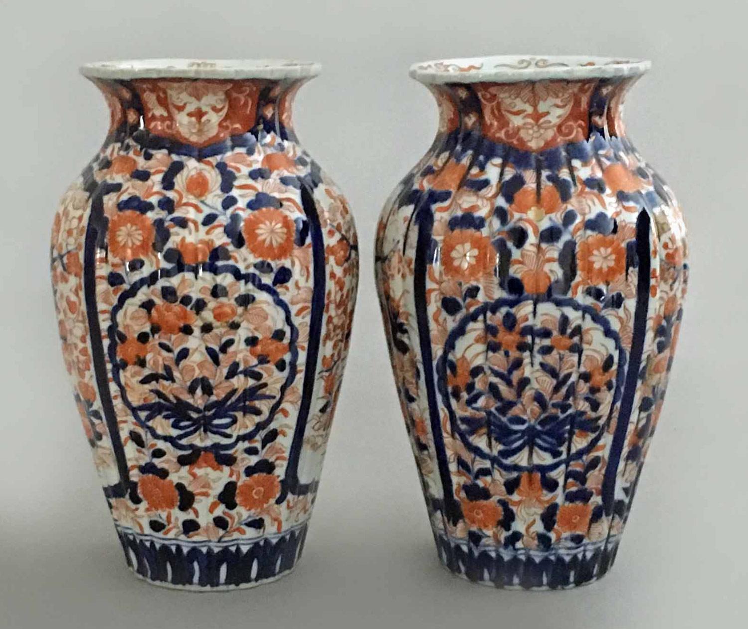 Pair of Japanese Imari Porcelain open vases of baluster form with short flared neck, ribbed bodies and scalloped rims, decorated with opposing shaped panels enclosing flower heads and branches in underglaze blue and iron red.