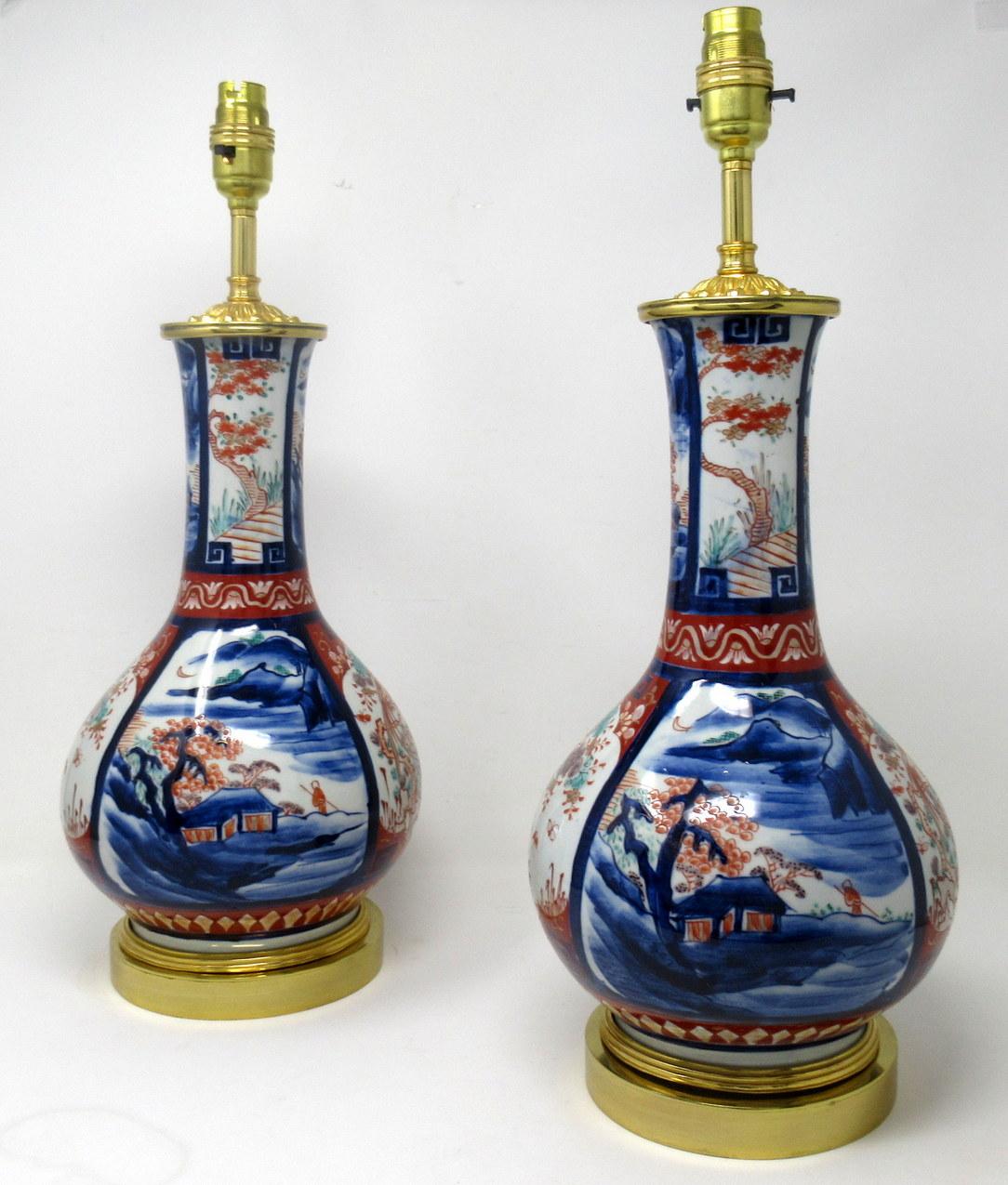 An Imposing and Stunning Pair Traditional Japanese Imari long neck Bottle Porcelain Vases of generous proportions, now converted to a pair of electric Table Lamps, complete with ormolu heavy gauge stepped circular bases and later ormolu mounts.