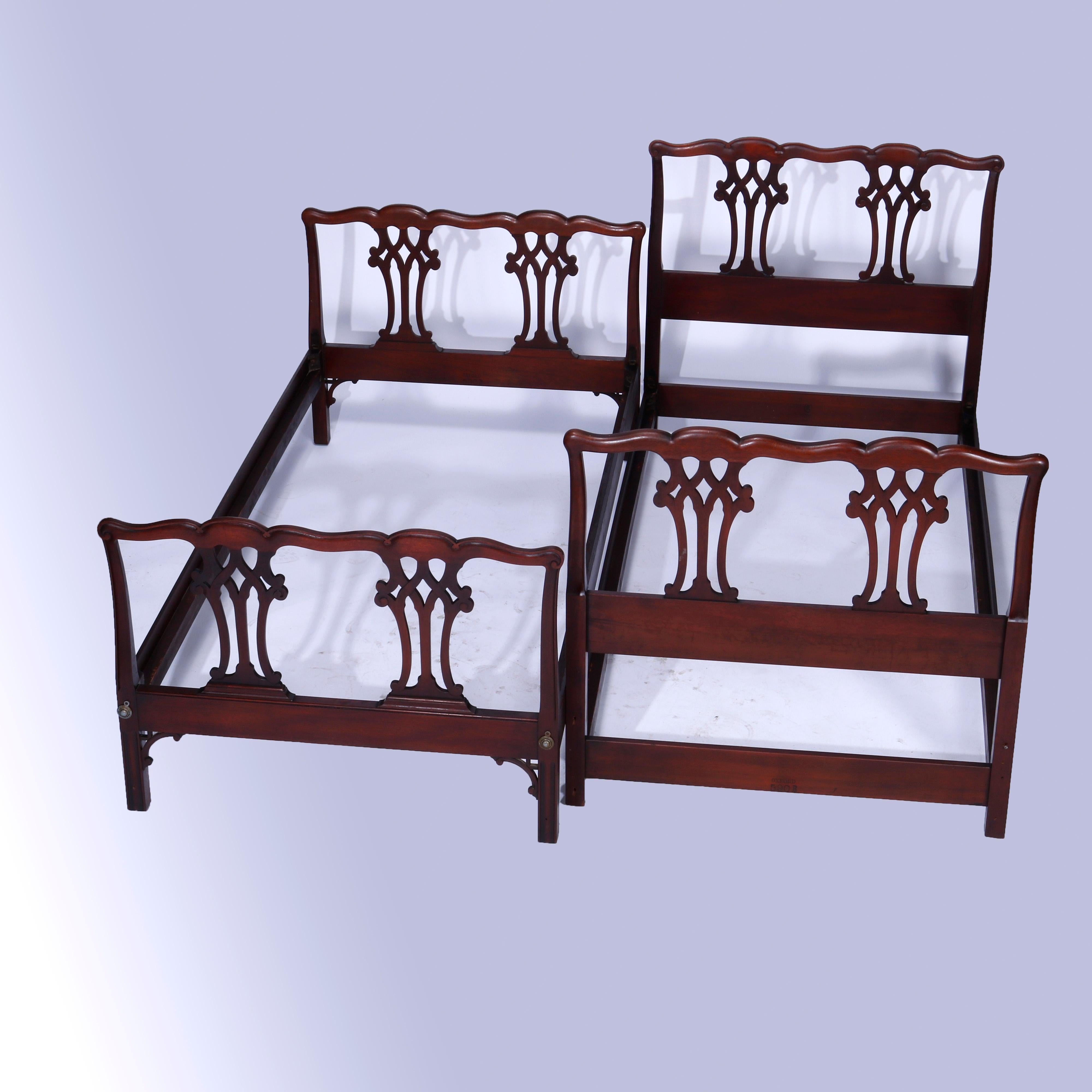 An antique pair of matching Chippendale style twin beds offer mahogany construction with shaped rails over pierced ribbon head and footboards, raised on straight and square legs having carved pierced corbels, c1930

Measures - headboard 38''H x