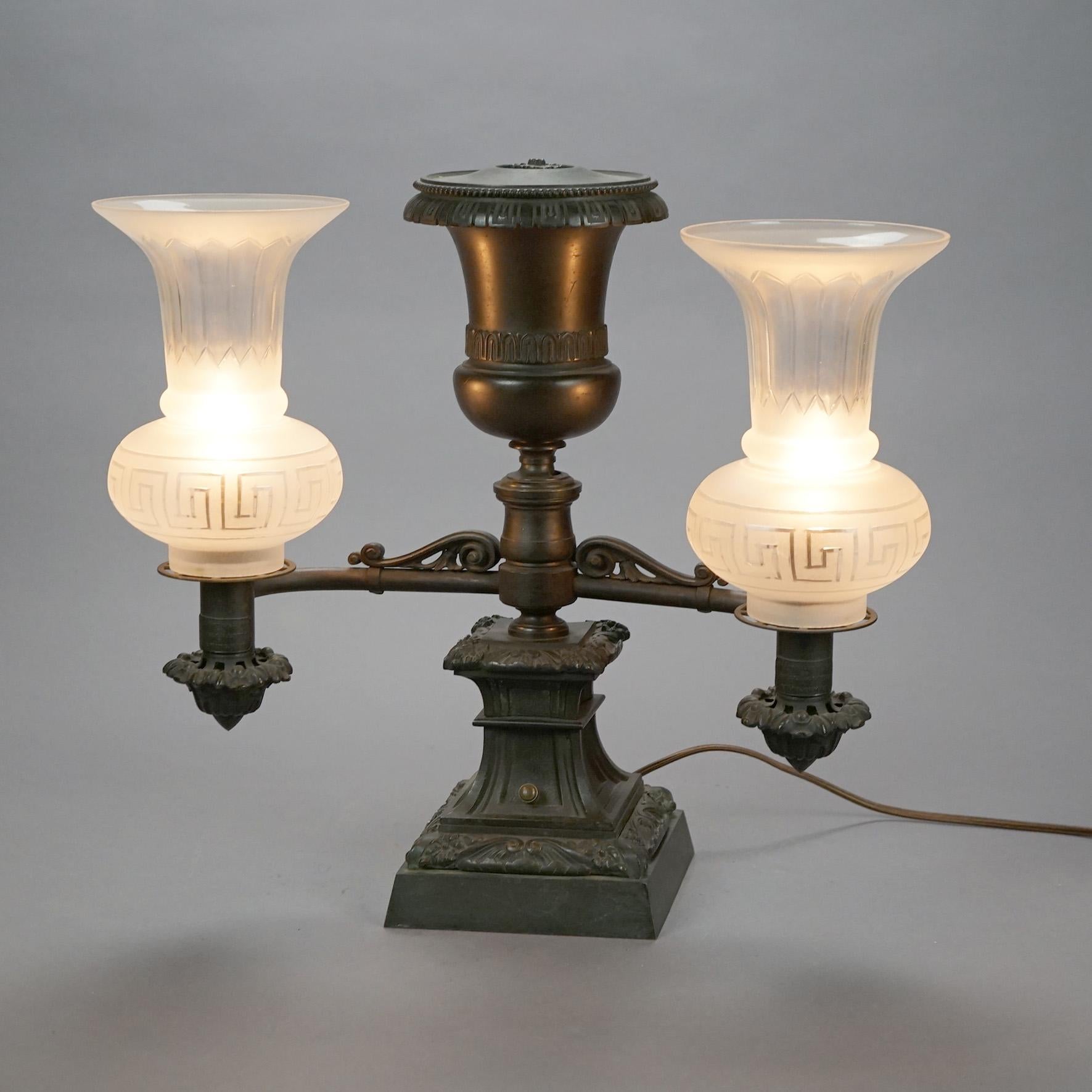 An antique pair of argand lamps by Messenger Co. offer cast bronze bases with Greco pedestal having double arms terminating in lights with Greek Key frosted shades, electrified, circa 1820s

Measures- 17''H x 18.5''W x 9.25''D.
