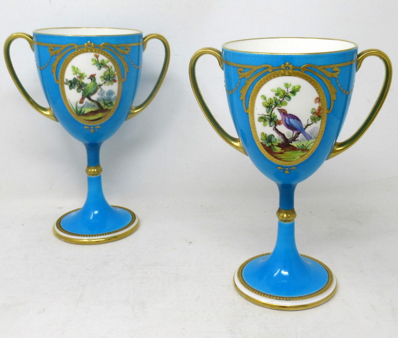 Atemberaubendes Beispiel für ein Paar englischer Minton-Porzellan-Langstiel-Doppelhenkel-Tassen oder -Vasen von herausragender Qualität, die dem Künstler James Edwin Dean (1863-1935) fest zugeschrieben werden. 

Jede zentrale ovale Reserve ist mit