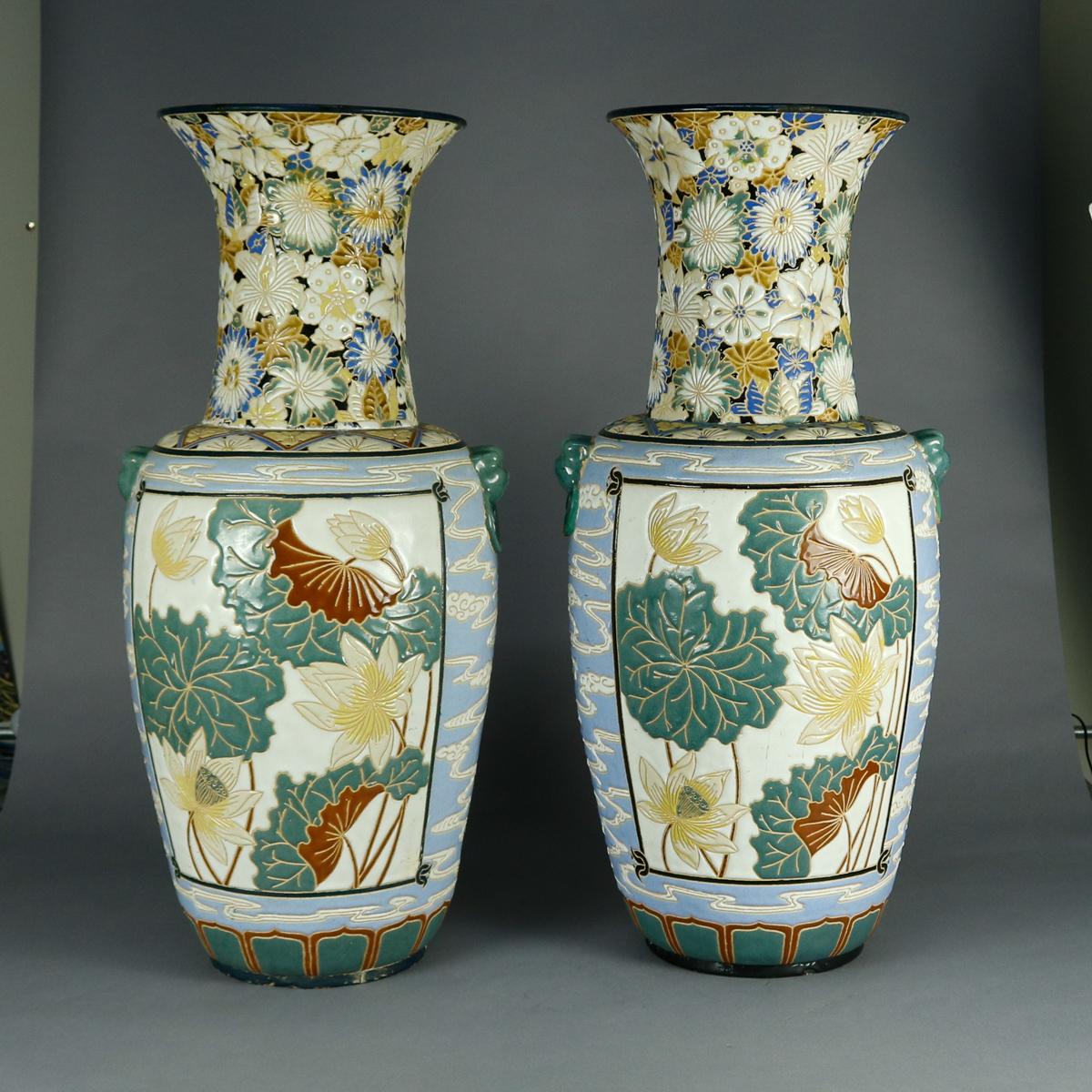 An antique pair of monumental Chinese floor vases offer urn form with enameled embossed floral reserves, all-over floral neck motif, vessel with all-over stylized cloud motif, and figural ring handles, circa 1920

Measures: 34