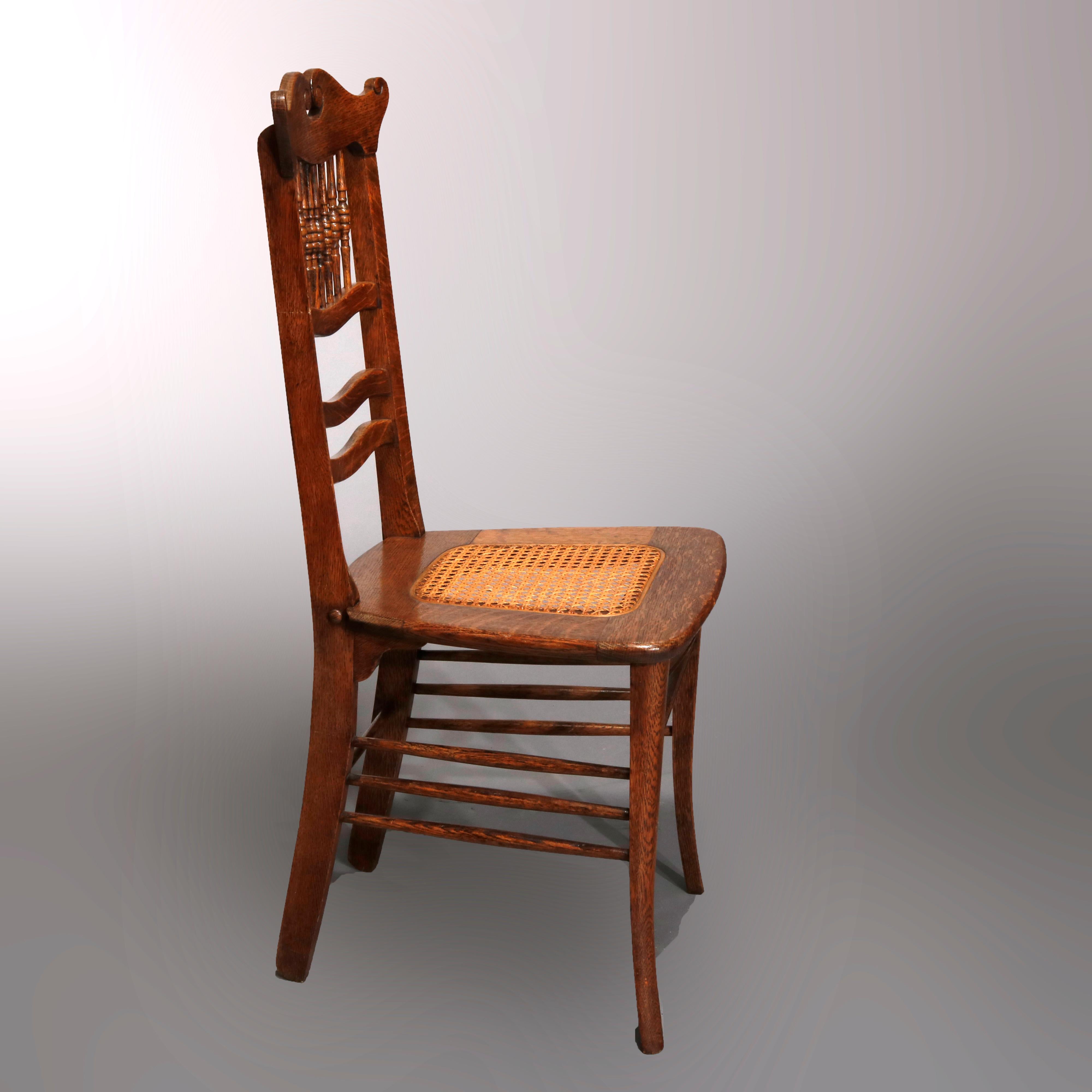 An antique pair of side chairs offer oak construction with spindle backs having shaped rail with scrolled broken arch crest surmounting caned seat, circa 1900

Measures- 37.75
