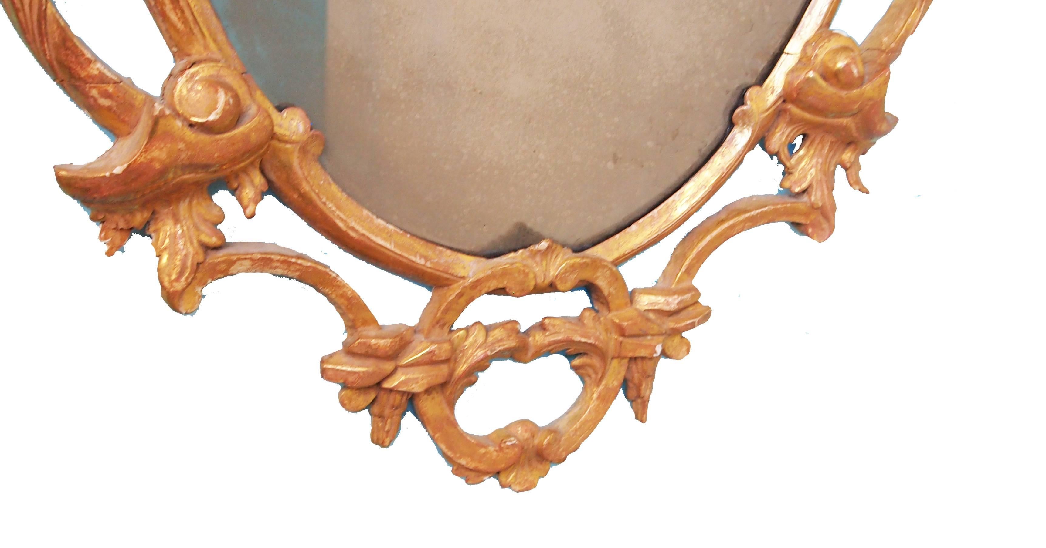 A fine pair of 18th century giltwood wall mirrors in
the Rococo taste having oval plates surrounded by
elaborate frames carved with c scrolls, acanthus and
foliage.
