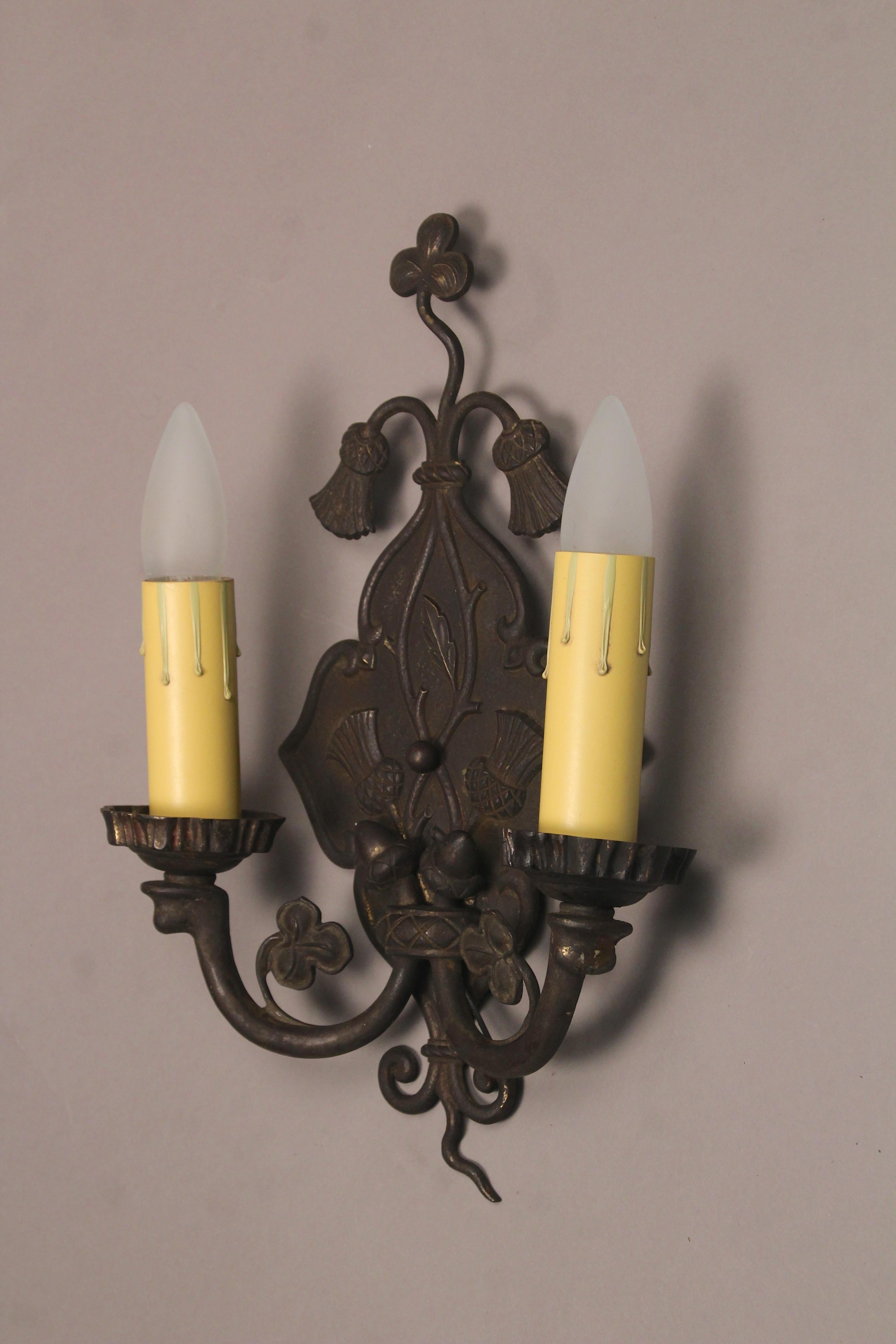 Pair of double sconces with thistle and clover motif. This pair would fit nicely in a Spanish Revival or English Tudor home, circa 1920s.