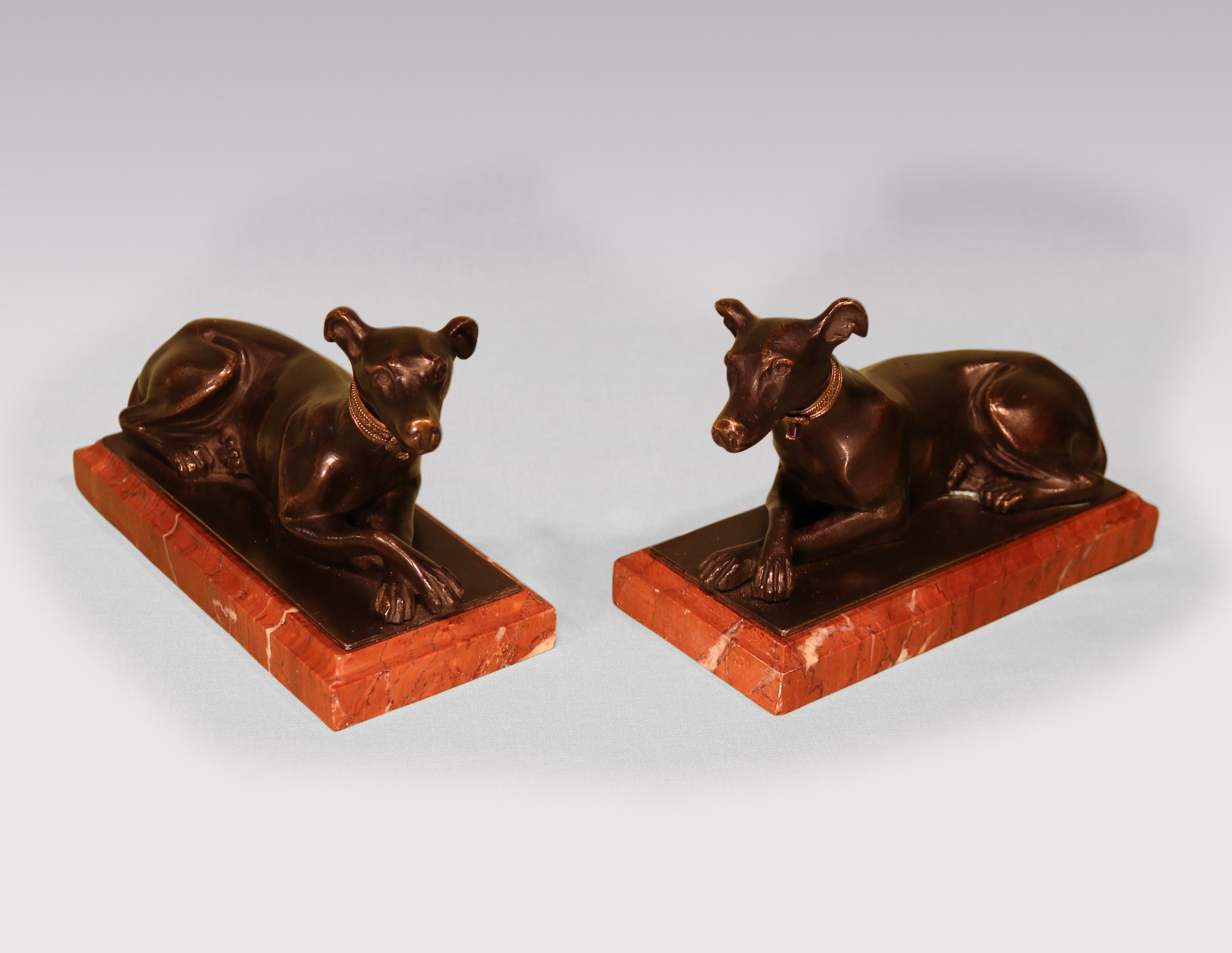 A fine quality pair of early 19th Century Regency period well-cast bronze Models of Greyhounds, having engine-turned gilt-brass collars, on moulded edged red marble bases.