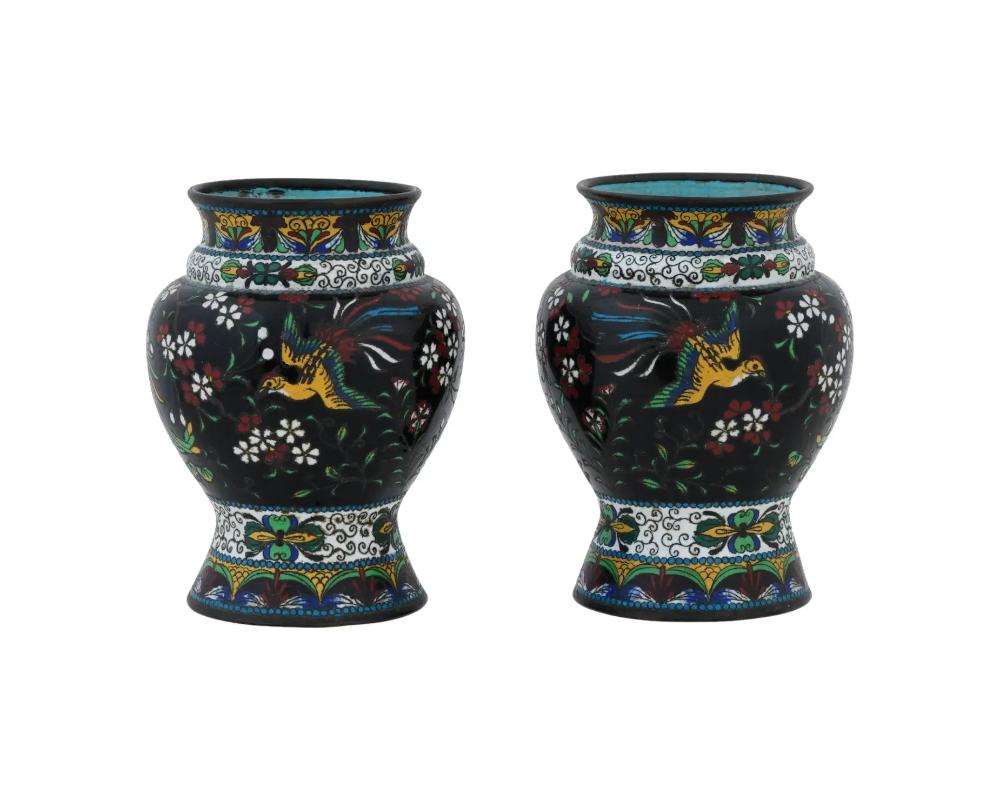 Paire de vases anciens en cloisonné du Japon du début de la période Meiji, ornés de majestueux oiseaux phénix et de resplendissants motifs floraux multicolores au sein de motifs feuillagés complexes, le tout habilement tissé dans un délicat travail