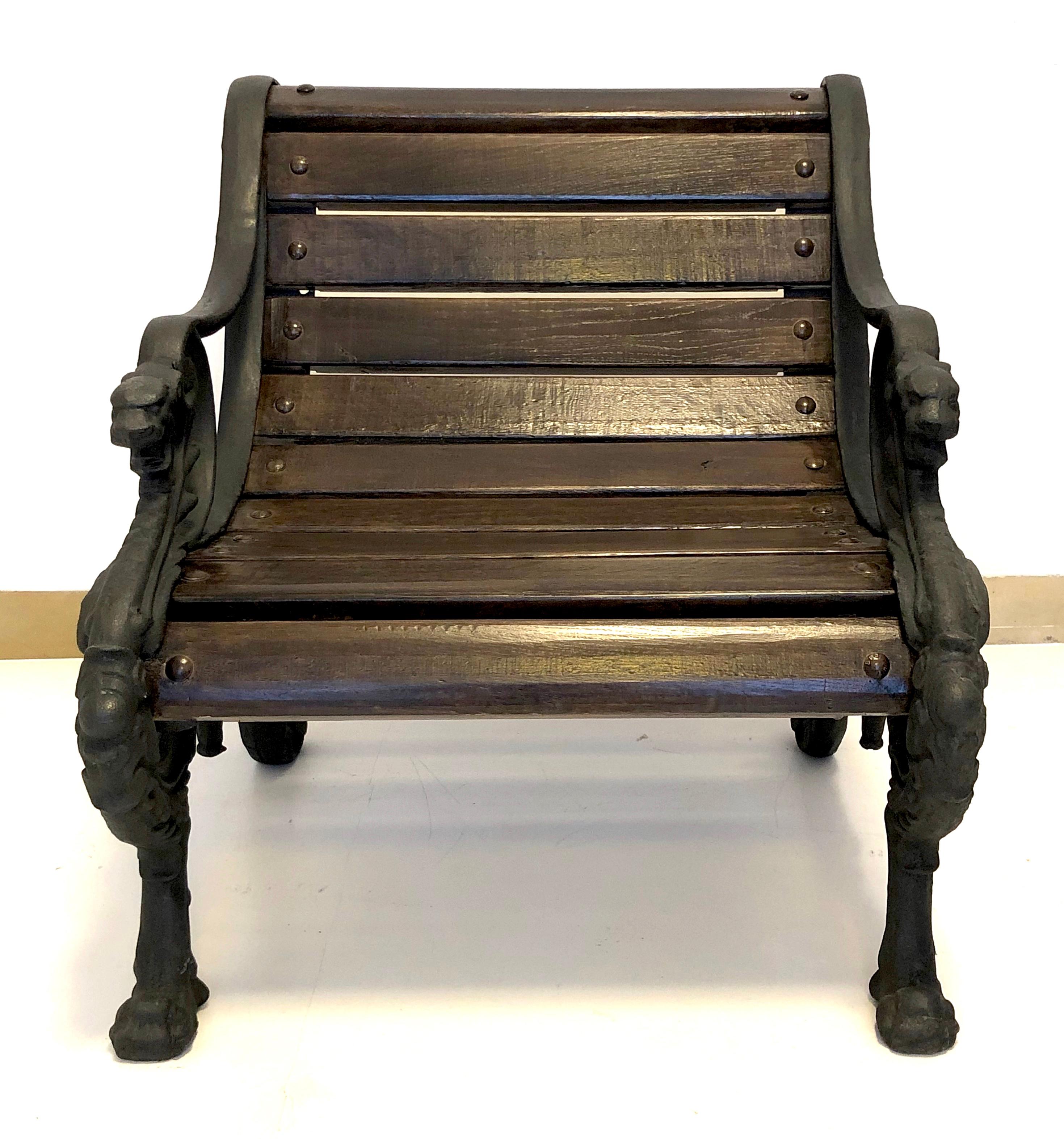 This pair of substantial cast iron and oak armchairs was made in France in circa 1860-1870. The iron armrests were designed as acanthus leaves surronded by scrollwork and terminating in lion heads. The rear feet were designed as acanthus leaves. The