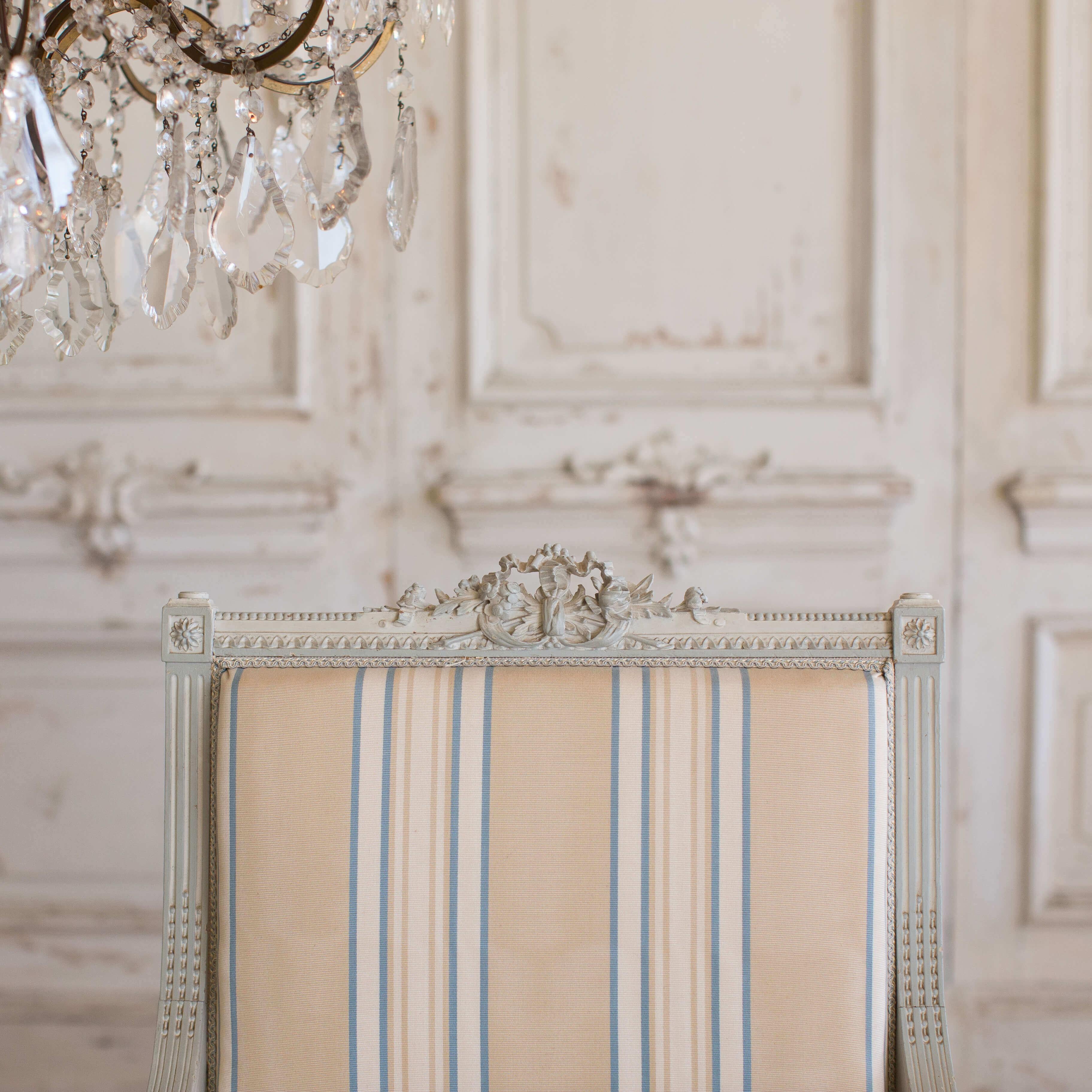 Charming antique French Louis XVI style armchairs. Very finely carved delicate frame with beautiful two-tone painted finish in pale grey and dark oyster. Upholstered in a beige, white and blue stripe fabric.