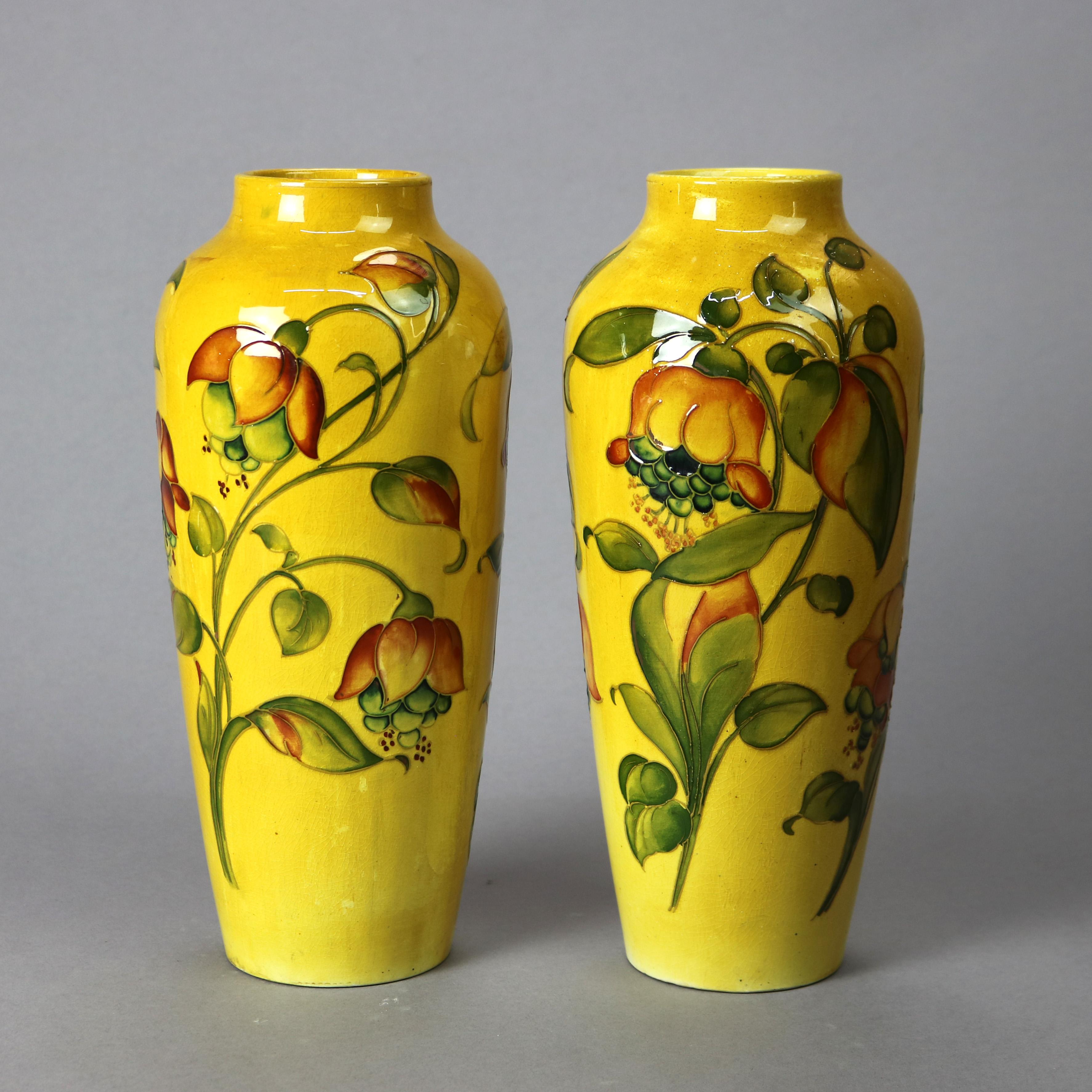 An antique Arts and Crafts pair of vase by Moorcroft offer art pottery construction with hand painted floral design, maker mark as photographed, drilled holes in bases, circa 1910

Measures 12