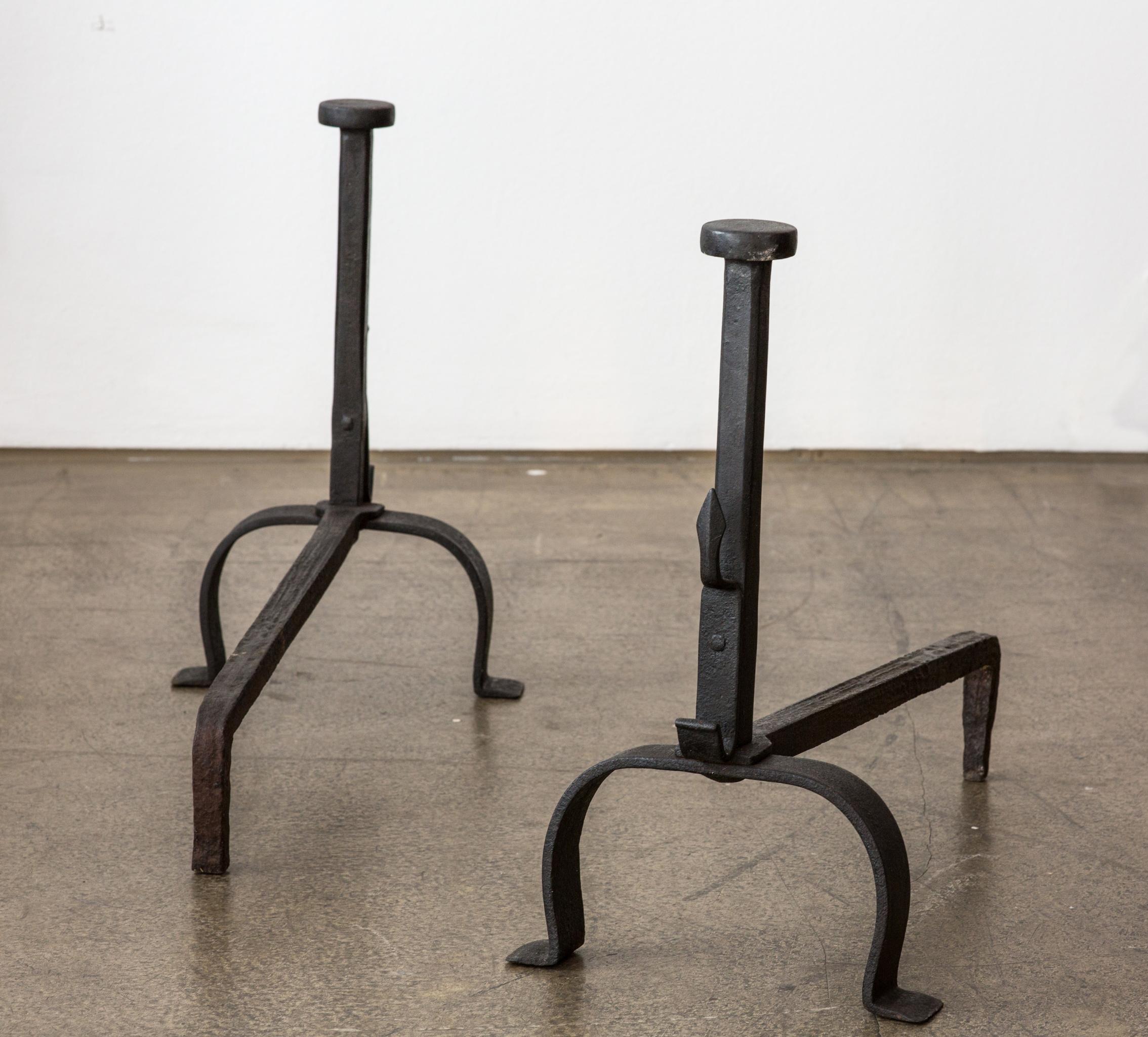 A very decorative pair of antique black wrought iron fireplace andirons. The iron andirons are from Italy and were made at the 19th Century. 

The andirons have two feet in front and one single feed at the back. The front feeds are connected with a