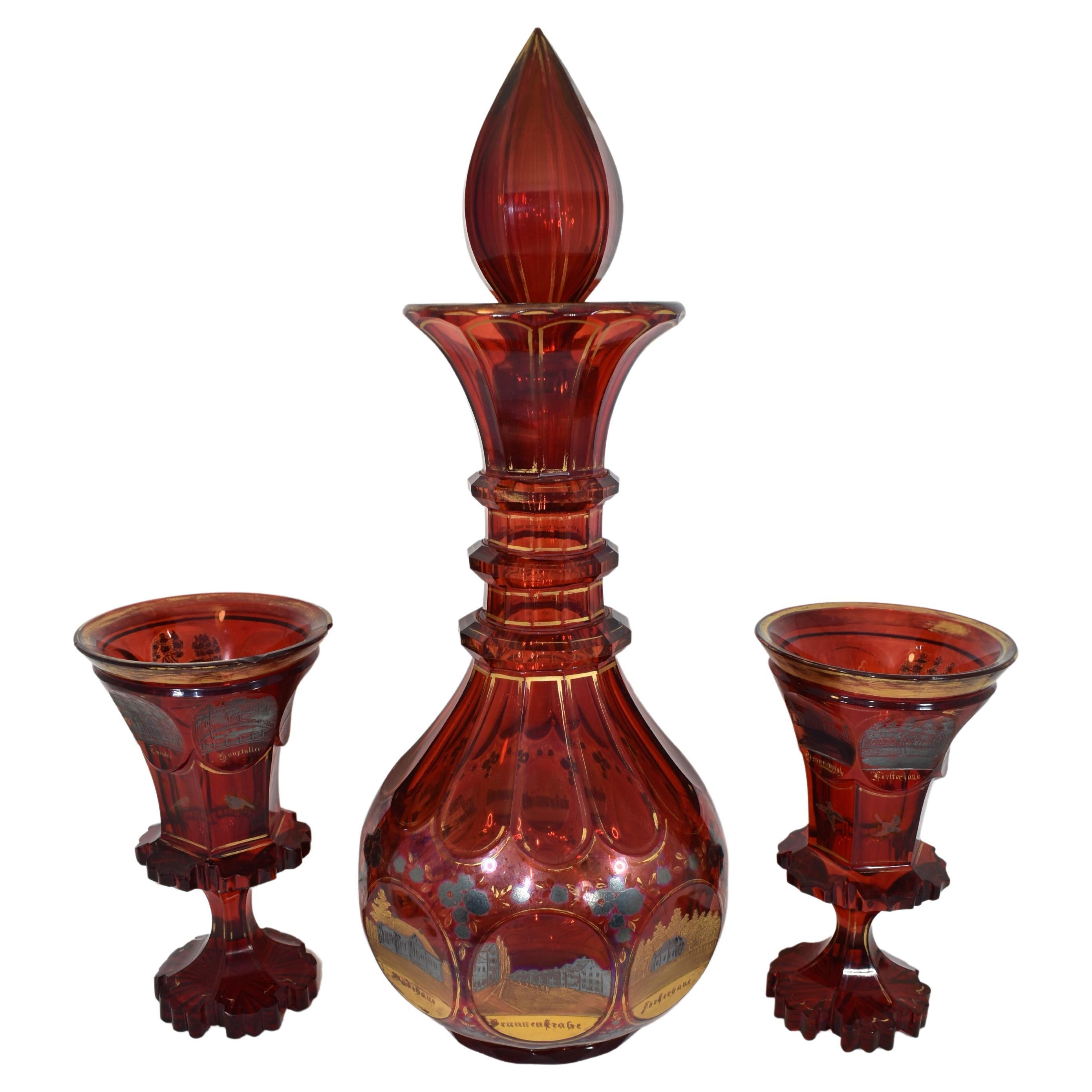 The rare set of one large decanter and a pair of goblets in deep transparent ruby red glass

decorated all around with multiple engraved scenes, silver enamel and gilding highlights

deceanter neckis applied with three rings

the goblets with