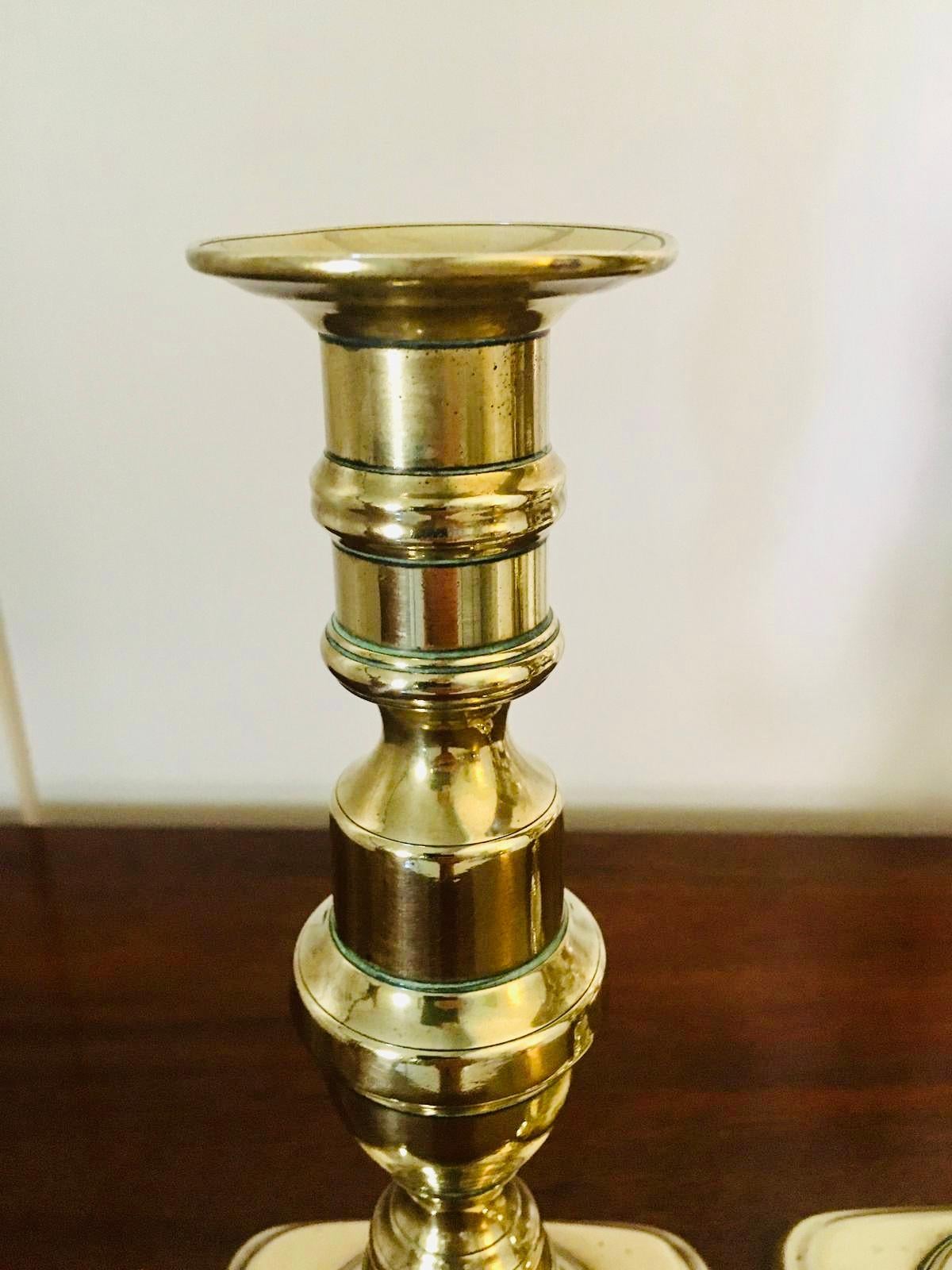 Antique brass pair of candlesticks having an elegant turned shaped column, standing on an oblong shaped base.

All original with original push ups.

Candle cup 6cm width, 2cm candle width capacity.
 