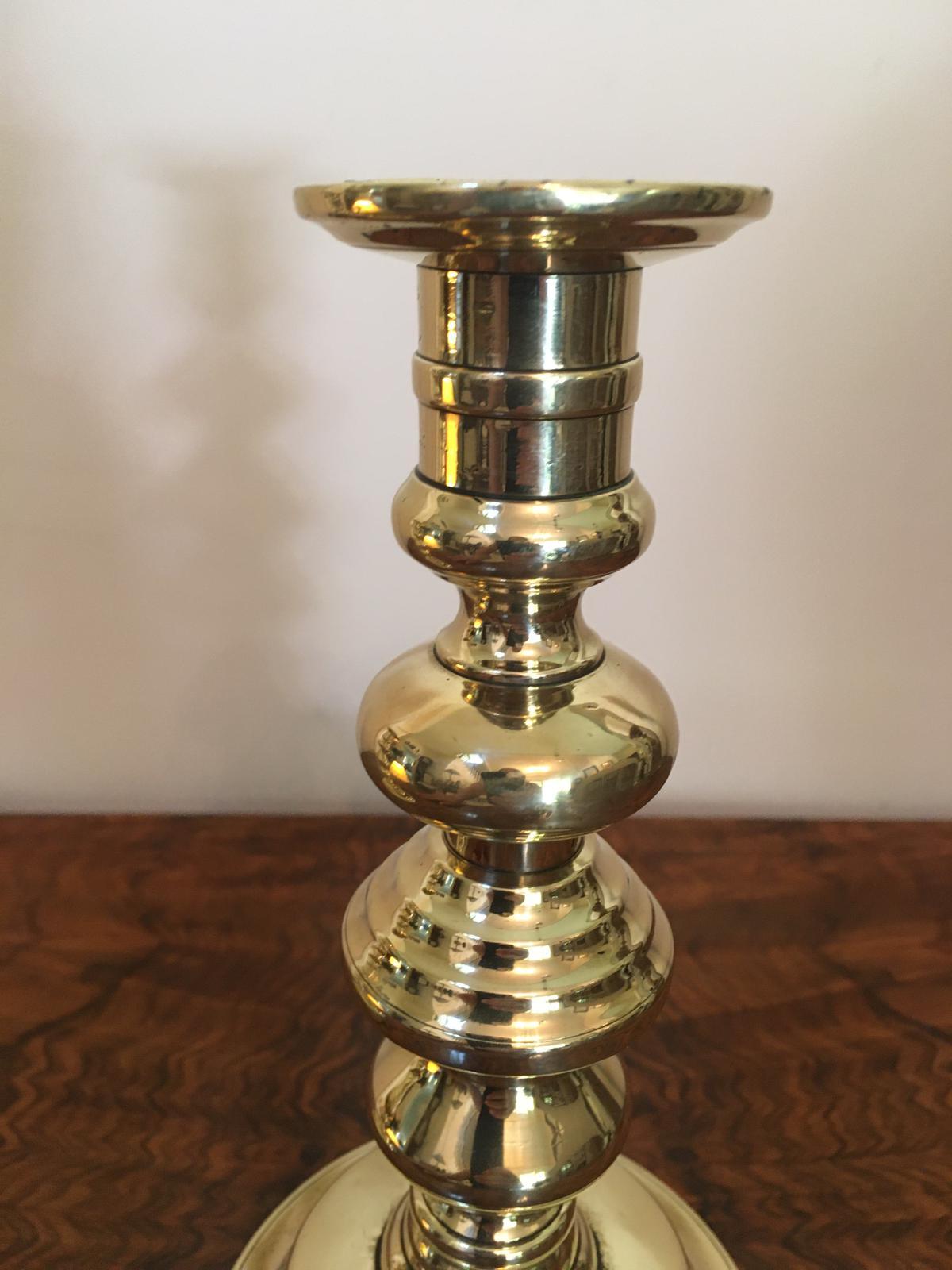 A pair of antique brass candlesticks having a quaint turned shaped stem and round base. All original.
  