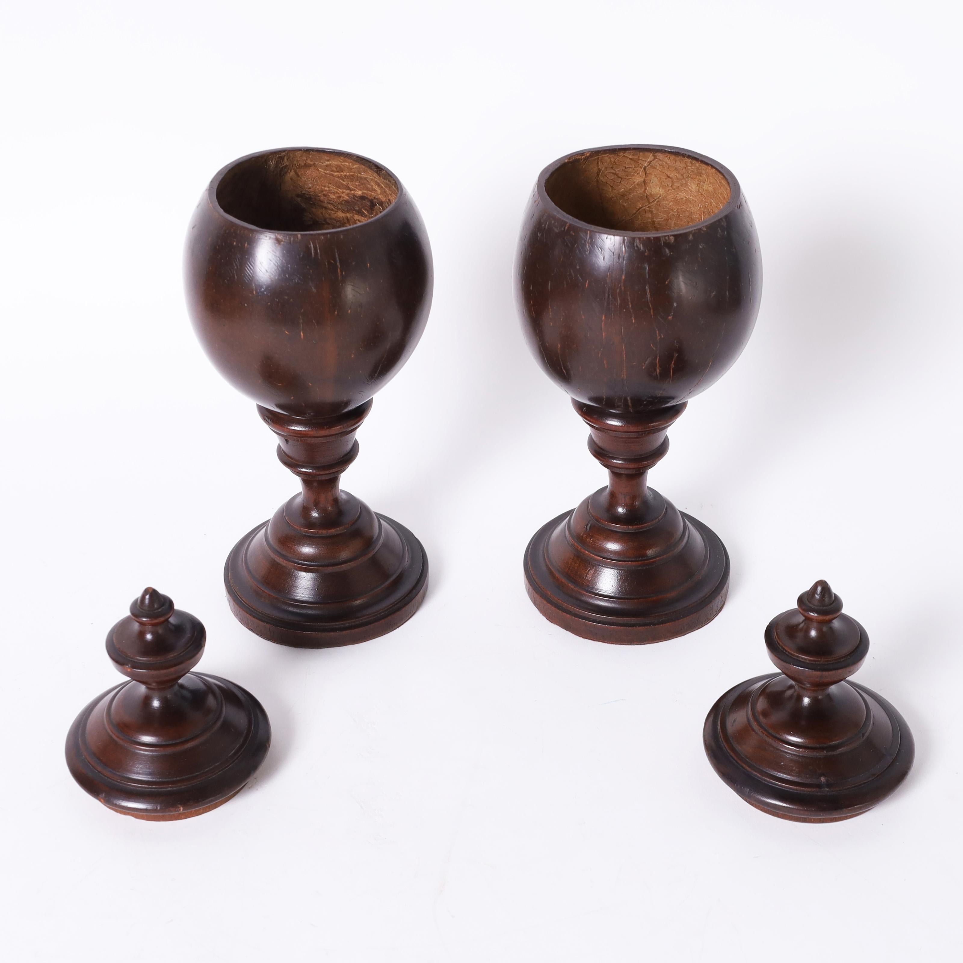 Rara coppia di urne con coperchio British Colonial dell'inizio del XIX secolo, realizzate a mano con noci di cocco e coperchi e basi in mogano tornito.