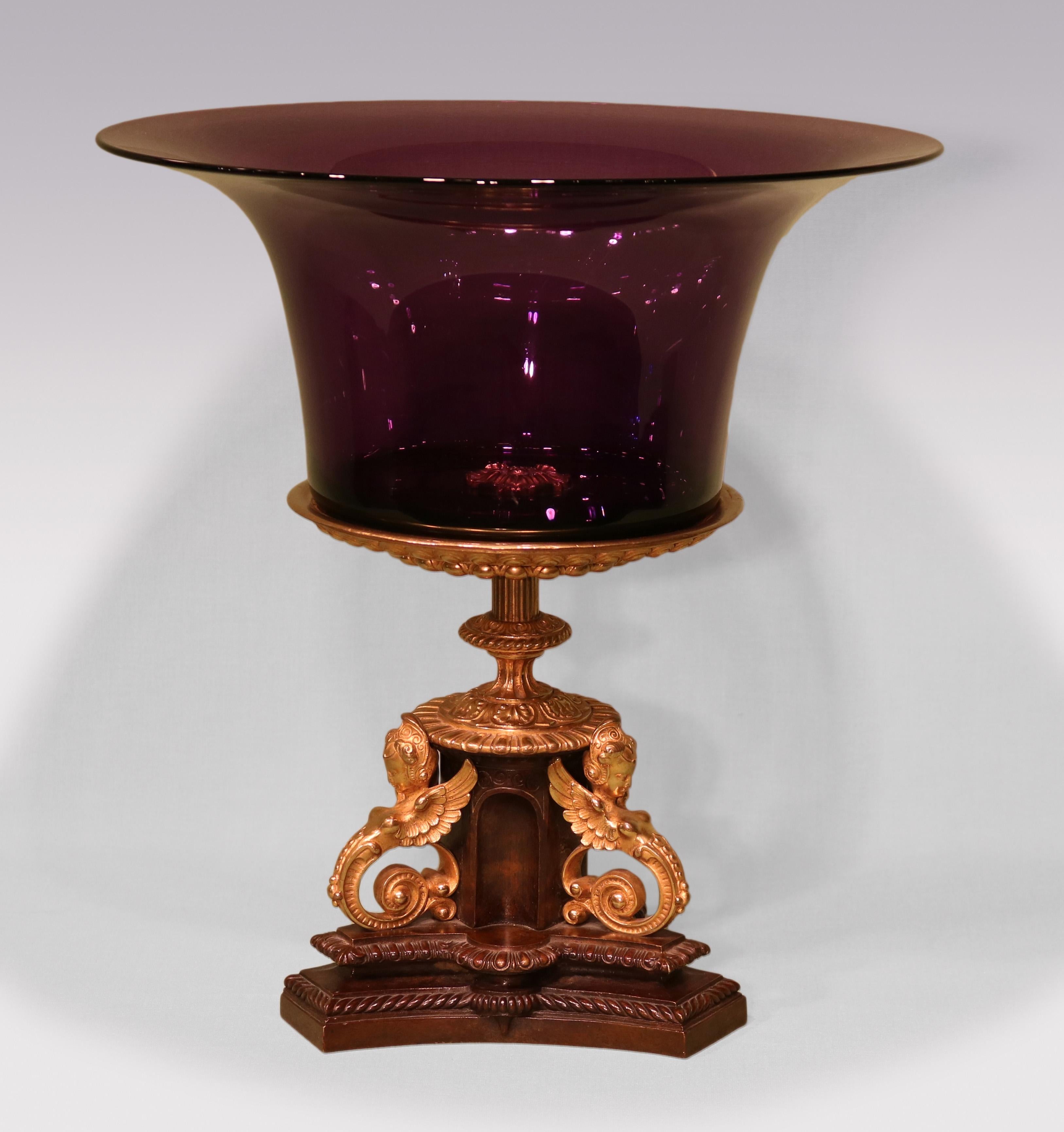 A pair of mid-19th Century Bronze & ormolu Tazzas, with amethyst glass bowls above triform bases with winged classical ladies raised on gadrooned double stepped concave bases.

Width and Depth of bases: 6 inches