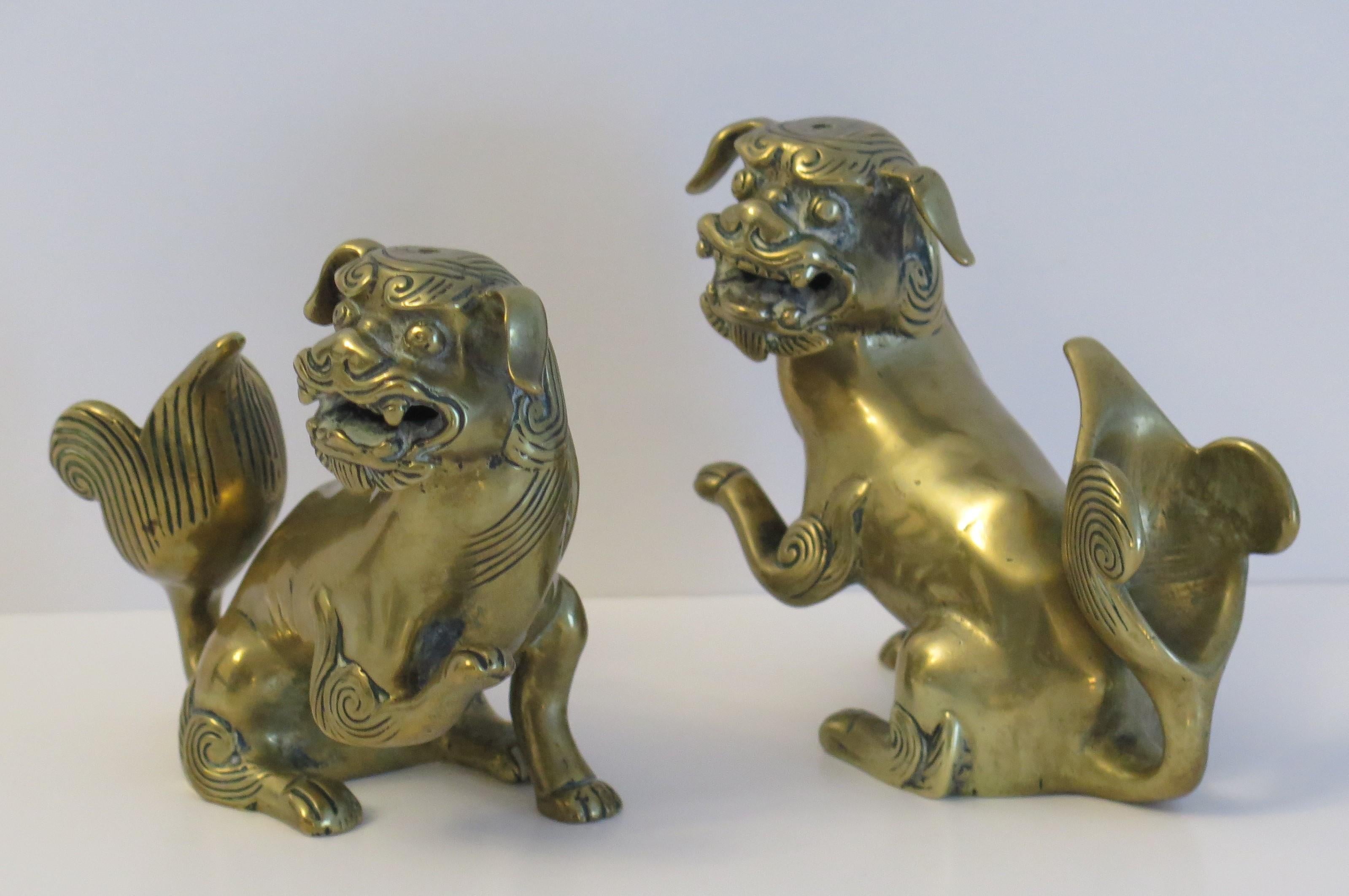 These are a very good pair of antique Chinese foo or lion dog sculptures, sometimes called temple lions, made of a brass-bronze metal alloy, with excellent detail, dating to the early 19th century, Qing period or possibly earlier back to the 18th
