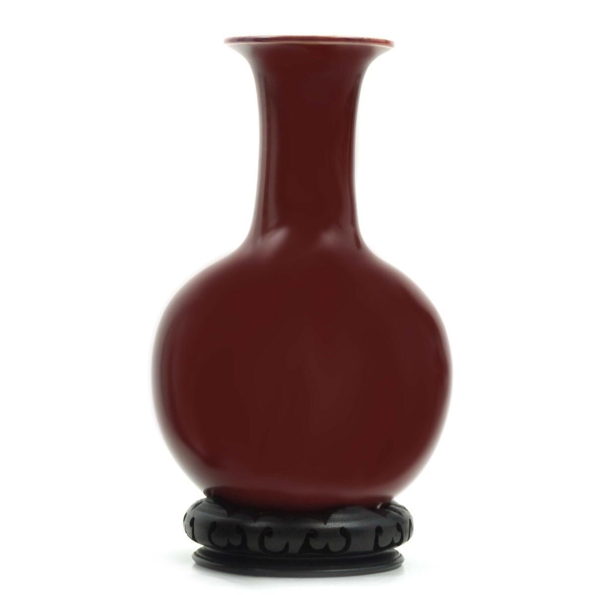 Pair of antique oxblood glazed porcelain vases with removable carved wood Stand. Chinese, dating to late 19th century or early 20th century. Signed. Provenance: From a New York collector who purchased the vases as vintage in 1970; original sales tag