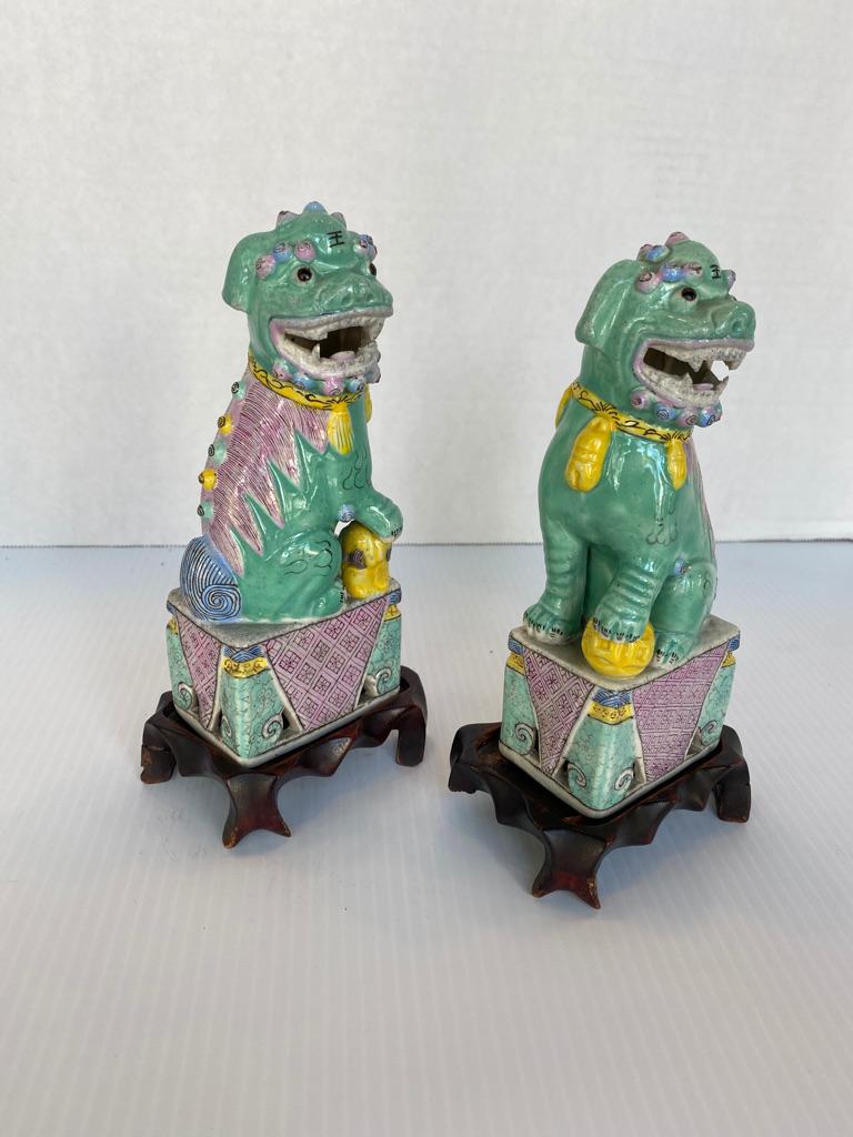 Antica coppia di cani da caccia cinesi in porcellana famille rose dipinti a mano, seduti in posizione eretta e con la bocca aperta, con supporti in legno di palissandro intagliato a mano, circa 1890-1910 con il marchio CHINA sul fondo di tutti.