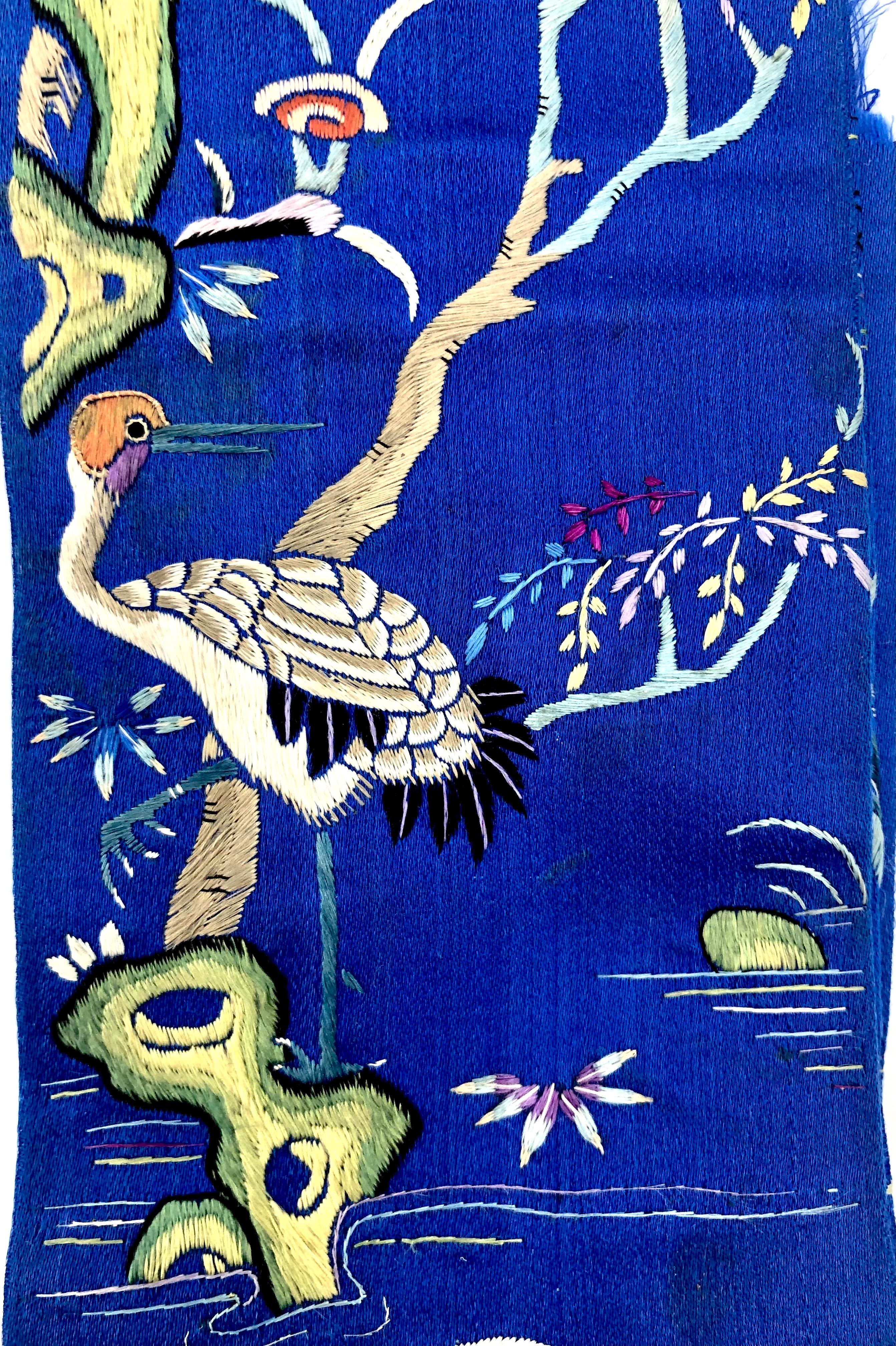 On wonderful bright blue silk we see two cranes looking at each other, peach trees with peach blossom, water with a softly ondulating pattern and lotus flowers.