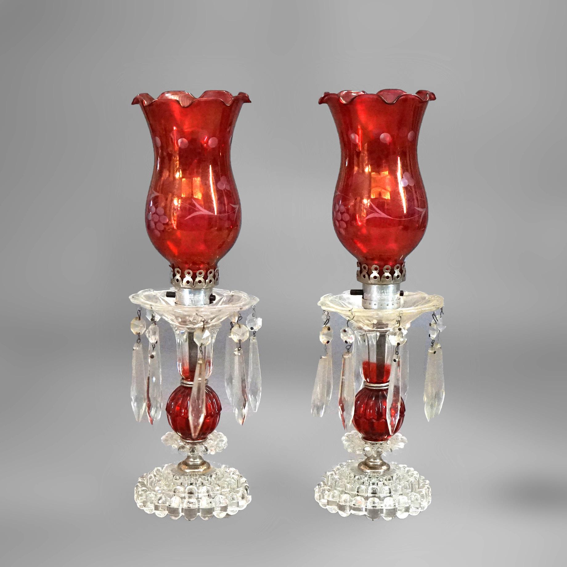 An antique pair of buffet lamps offers cranberry and colorless glass construction with etched shades and hanging crystals, c1940

Measure - 15