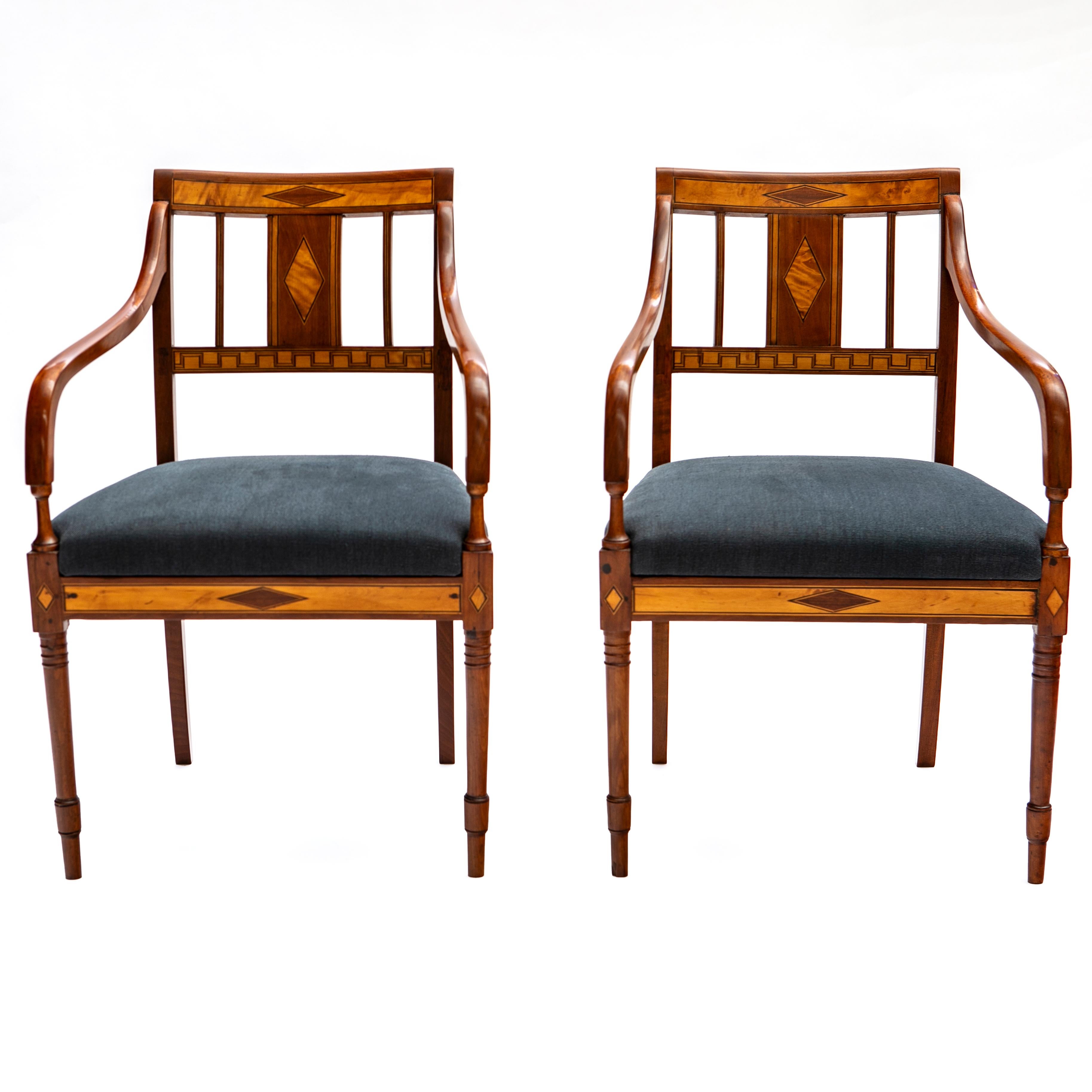 A pair of elegant Danish early 19th century empire armchairs.
Crafted in mahogany with ebony and satinwood marquetry on backrest and apron.
Apron and upper part of backrest decorated with diamond-shaped inlays. Lower part of backrest decorated with