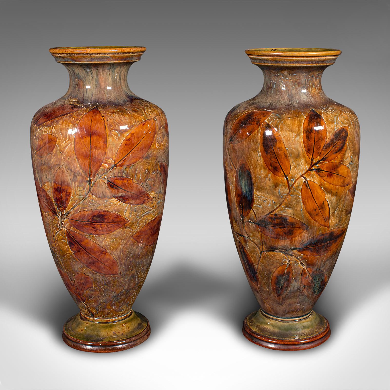 
This is an antique pair of decorative vases. An English, glazed ceramic flower urn, dating to the Edwardian period, circa 1910.

Attractive Autumnal colours accentuate the classic urn form
Displaying a desirable aged patina and in good