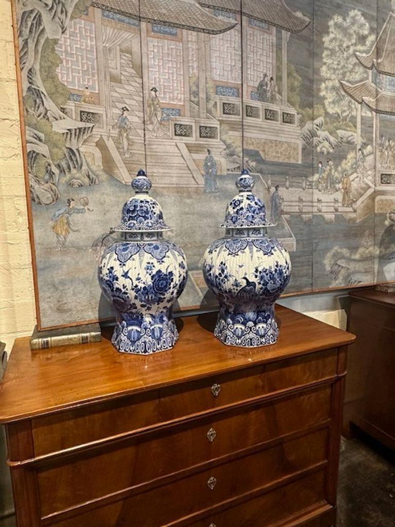 Gorgeous pair of antique Delft Blue porcelain lidded vases. Featuring a very pretty pattern with floral images and birds. Lovely! Note: There is a hairline crack on one of the vases. It is shown in the pictures, but vase is stable.