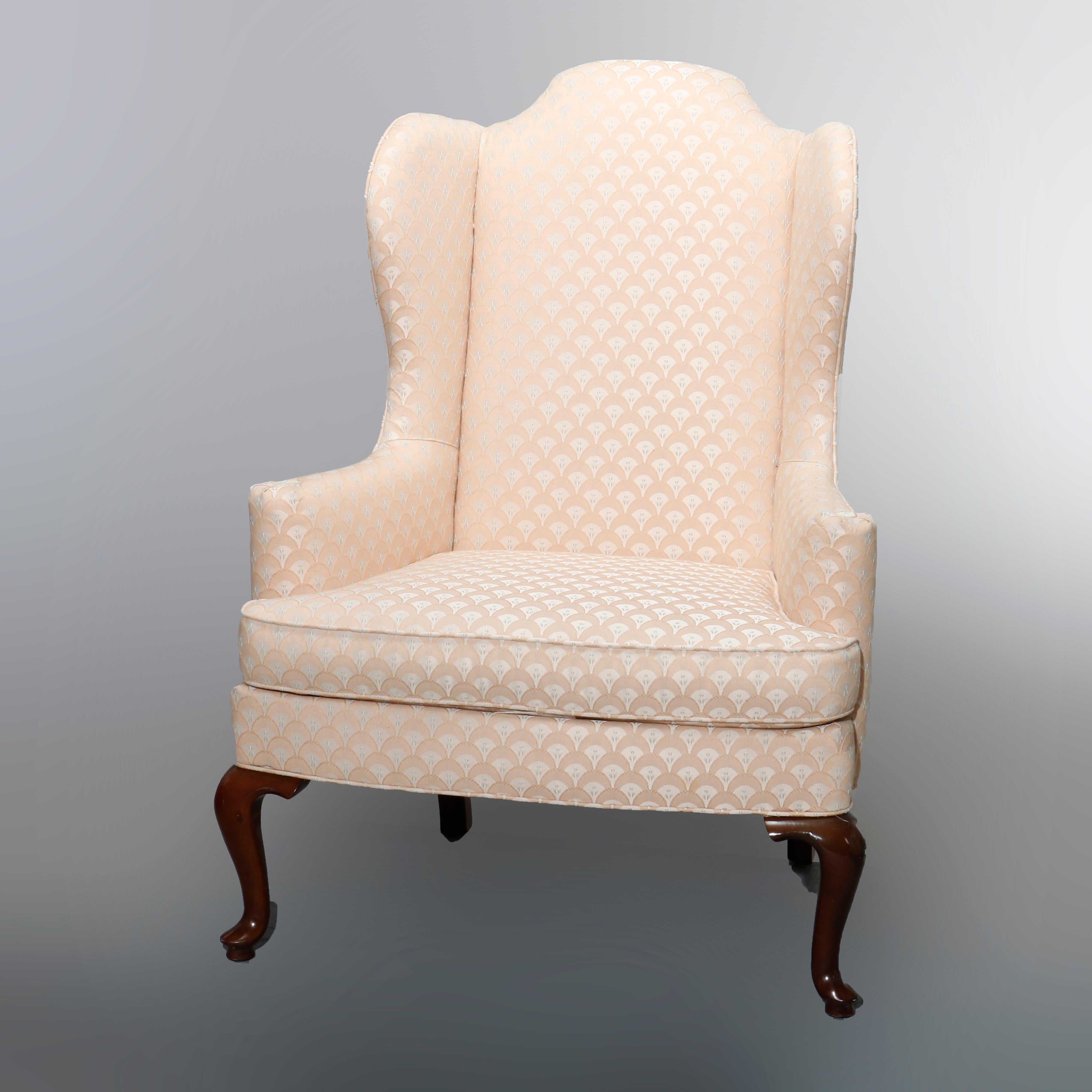 An antique pair of upholstered wingback fireside chairs by Drexel Heritage offer Queen Anne styling with shaped backs and scroll form arms, raised on mahogany cabriole legs, maker labels as photographed, 20th century

Measures: 45.5