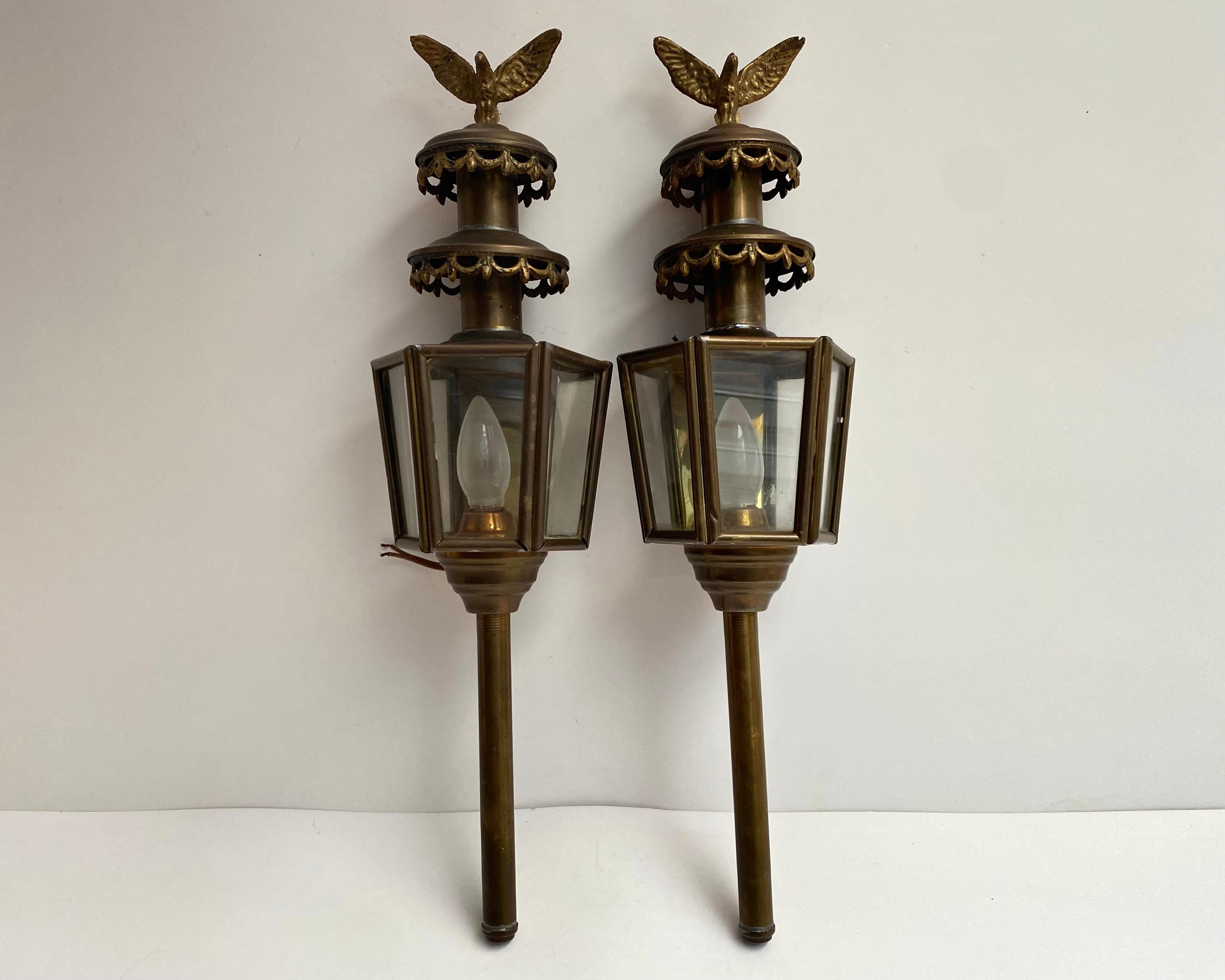 Pair of Antique brass carriage lanterns, manufactured in France, second half of the 19 century.  

The huge carriage lamps are adorned with decorative crowns and an imposing eagle at the top.

Original glass surrounds the lamp on five