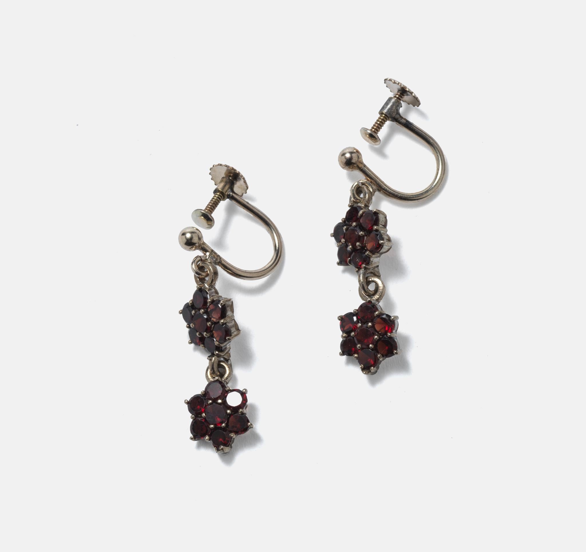 A sweet pair of small earrings made of silver with set garnets in the shape of flowers. Garnets were very popular in the 19th c and early 20th c. The deep red colour works very well with the silver they are set in.
