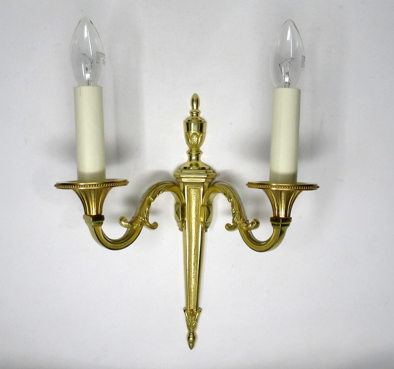 Fine quality pair of English gilt bronze twin arm wall candle sconces lights, of medium proportions, late 19th, early 20th century. 

The twin leaf capped scroll arms issuing from a well-cast single decorative tapering column backplate topped with