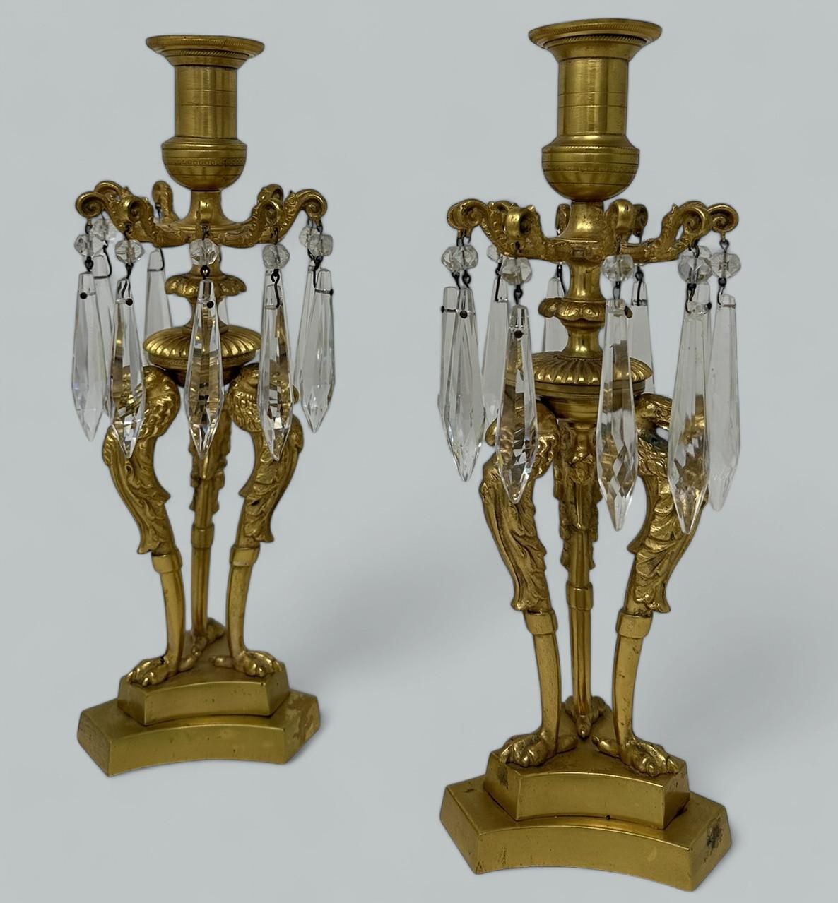 Coppia di candelieri a luce singola e pesante del periodo Regency in bronzo dorato e ormolu - Lusters, prima metà del XIX secolo, di origine inglese. 

Ciascuna con un baldacchino in ormolu a foglie d'acanto con dieci prismi di cristallo sfaccettato