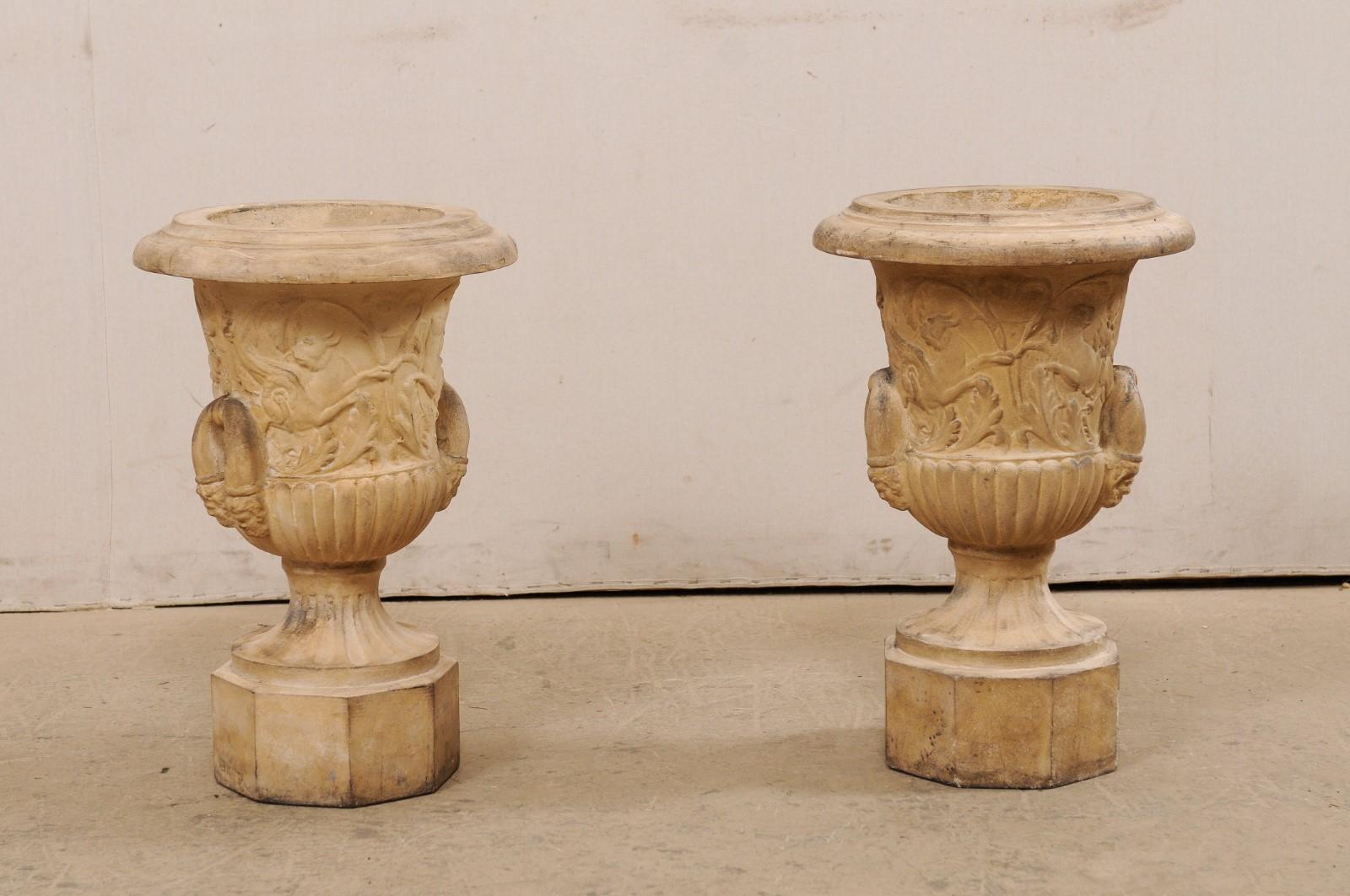 Une paire d'urnes anglaises en terre cuite du début du 20e siècle. Cette paire d'urnes anciennes en terre cuite provenant d'Angleterre est ornée d'un motif de griffons ailés et d'un motif de feuillage, avec des éléments anglés. Une solide poignée