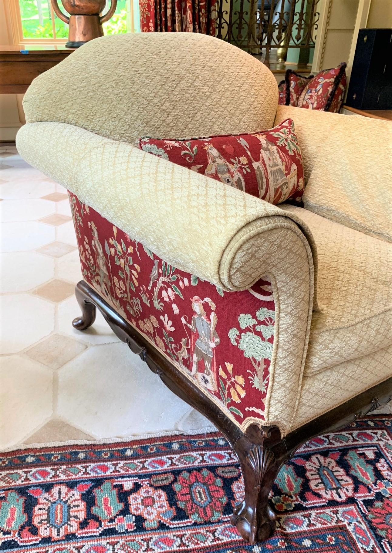 Remarkable pair of antique roll-arm mahogany club chairs or bergeres crafted in the English Chippendale styling. Highlighting colorful upholstery panels depicting flowering landscapes with Royalty and a variety of wildlife. The front legs with shell