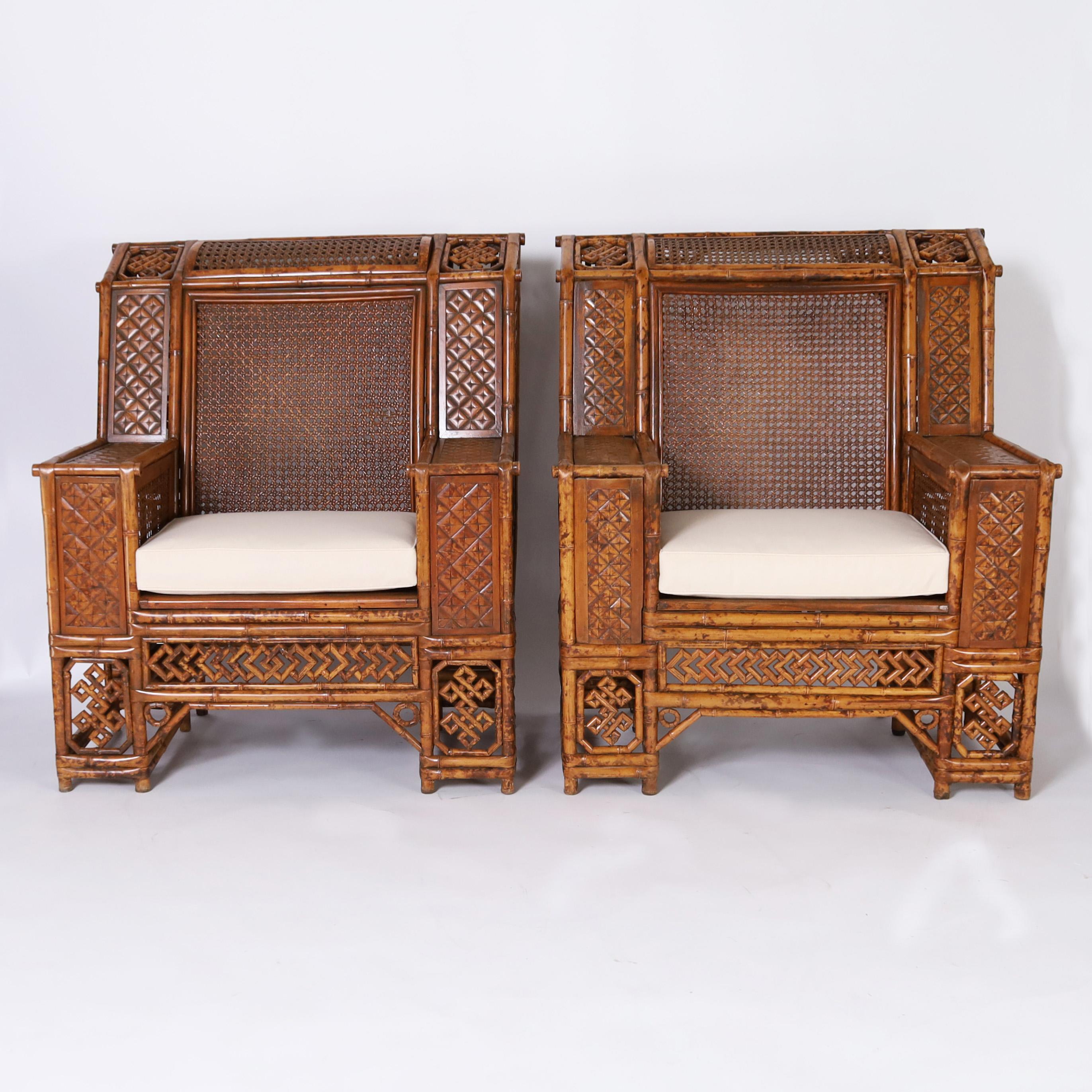 Rare and remarkable ultimate pair of Chinese bamboo club chairs handcrafted in a pegged construction featuring elaborate chippendale motifs on the backs, sides, and front, polished coconut arms, caned backs and seats and twelve legs each. Best of