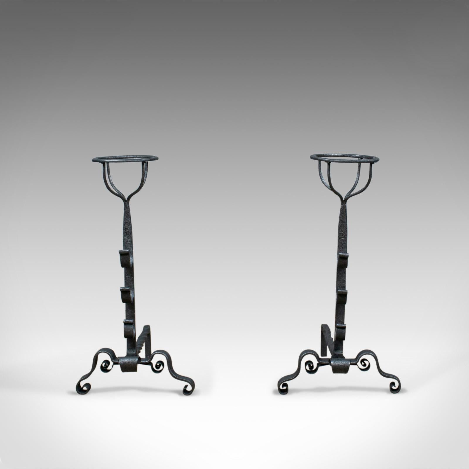 This is an antique pair of firedogs. English, medieval revival andirons forged in the early 20th century, circa 1900.

Bold andirons ideal for a large fire basket
Standing upon a scrolled arch leg
Medieval revival in taste
Featuring three spit