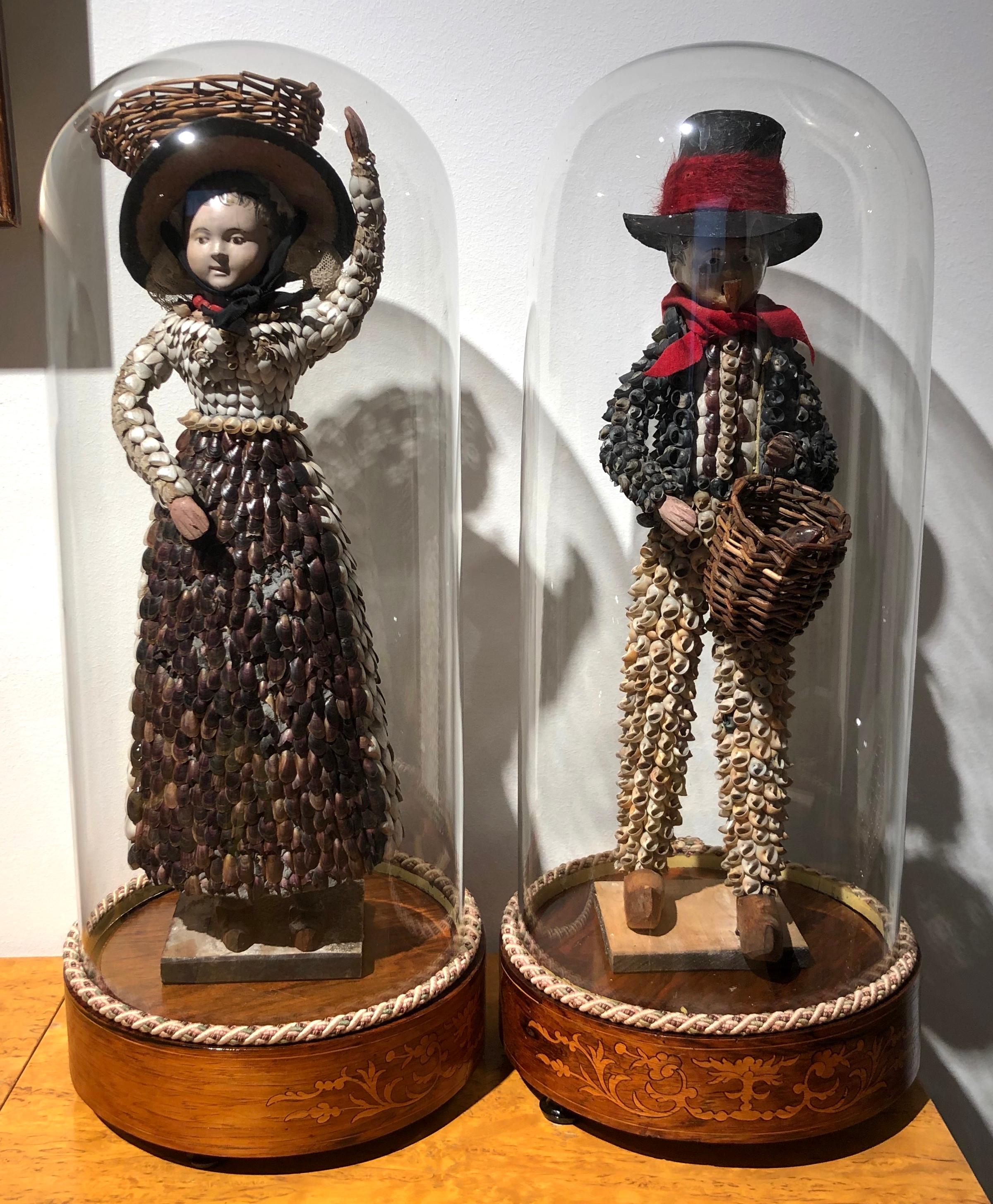 This marvellous pair of Folk Art figures are made out of painted paper mash and carved and painted wood. The couple represents a fisherman and a fish seller, probably his wife.
Their clothes are covered with small clams and other shells. The woman