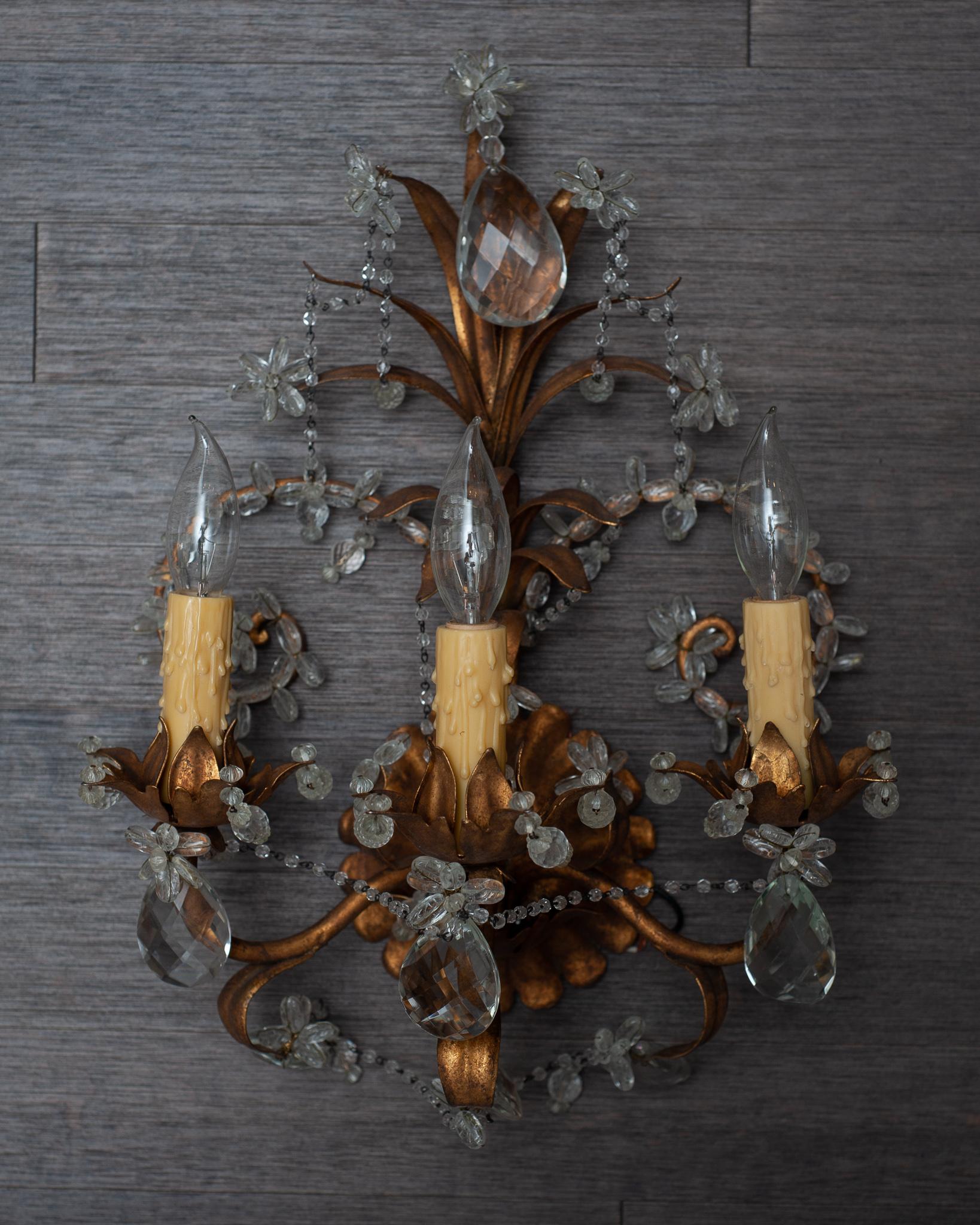 A stunning and ornate pair of antique French brass and crystal sconces.