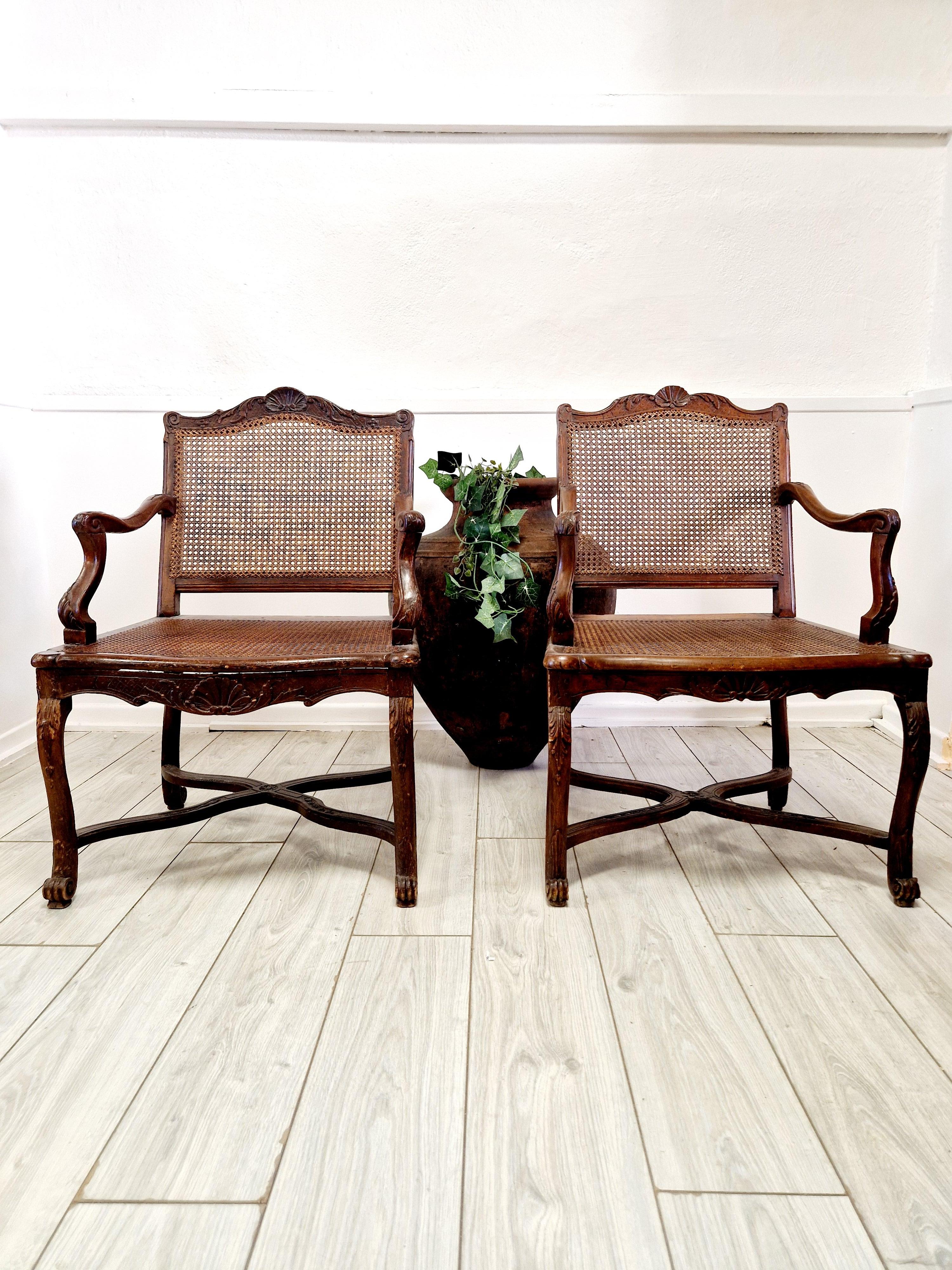 Cette paire de beaux fauteuils anciens en rotin français date de la période Regency, plus précisément de 1811. Ces chaises de forme carrée sont fabriquées en bois de noyer dans un style Louis XV, avec des sculptures complexes de coquillages et de