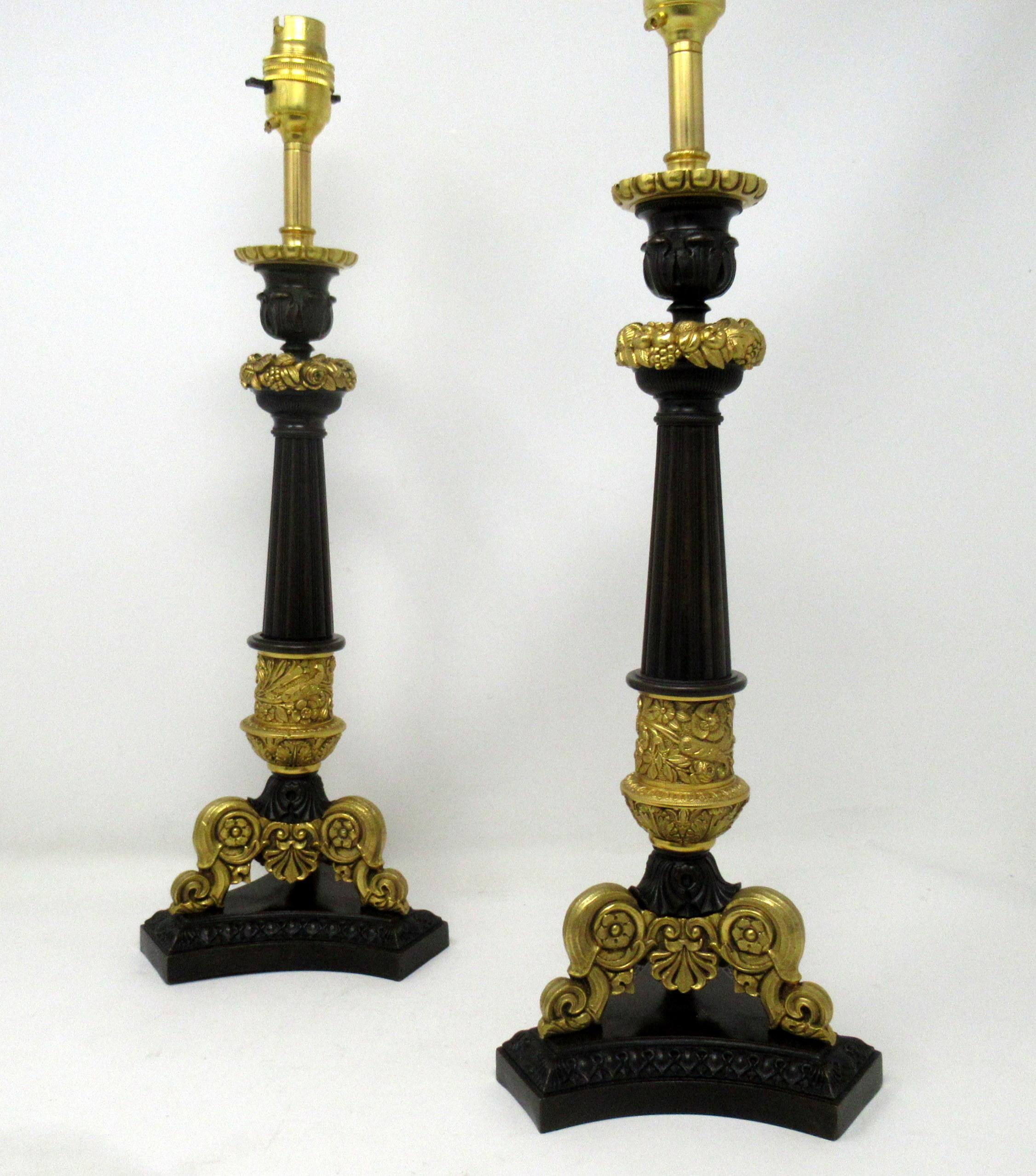 Stunning pair of French heavy gauge ormolu and bronze single light candlesticks, now converted to electric table lamps, of nice tall proportions, each concave tri-form base raised on foliate cast shell feet. The finely cast urn formed nozzles with