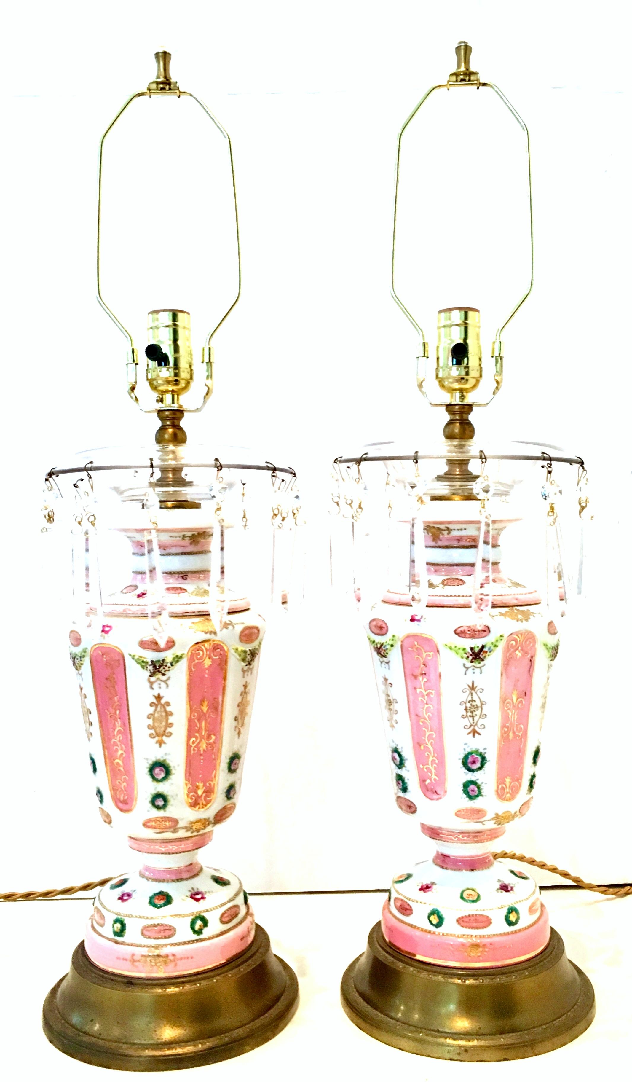 Antique pair of French Continental style hand-painted porcelain and crystal prism table lamps. These rare and stunning 22-karat raised gold detail and hand-painted lamps, feature a bright white ground with pink and green tones. Original