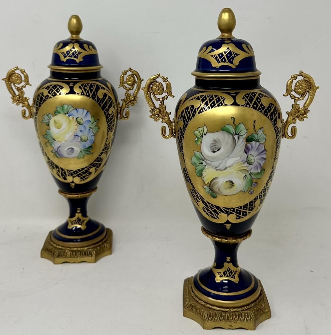 Stunning Pair of French Limoges Hard Paste Enameled Porcelain and Ormolu Twin Handle Table or Mantle Urns of traditional urn form and of outstanding quality, and good size proportions, each raised on a square stepped base with canted corners.