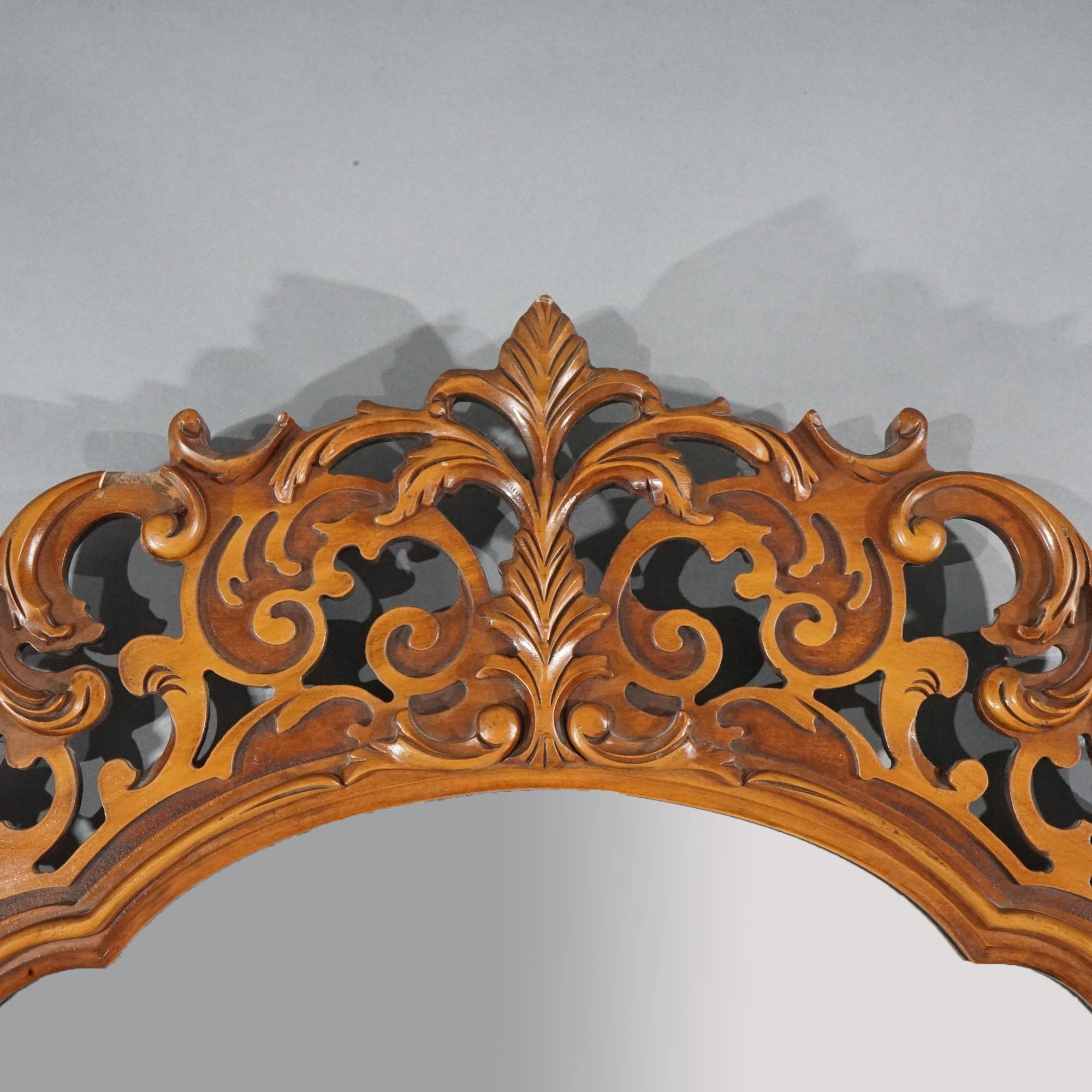 An antique matching pair of French Louis XIV style wall mirrors offer mahogany construction with shaped form with carved crests having foliate and scroll design, circa 1930. 

Measures - overall 45 1/2