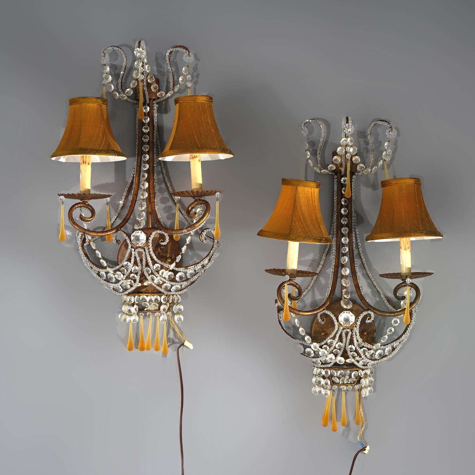 An antique set of French Louis XIV style wall sconces offer scrolled metal frames with two arms terminating in candle lights and crystals throughout, 9thC

Measures - 26