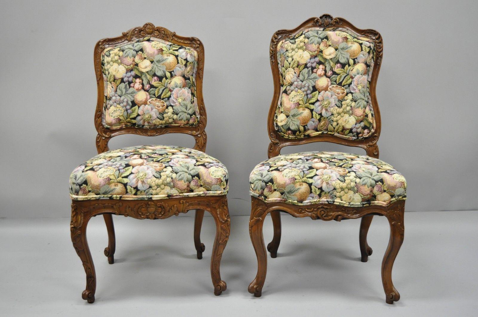 Antique near pair of French Louis XV style carved walnut upholstered side chairs. Listing includes complementary pair with variations in carvings and size, fruit, leaves and flowers printed tapestry fabric, solid wood construction, finely carved