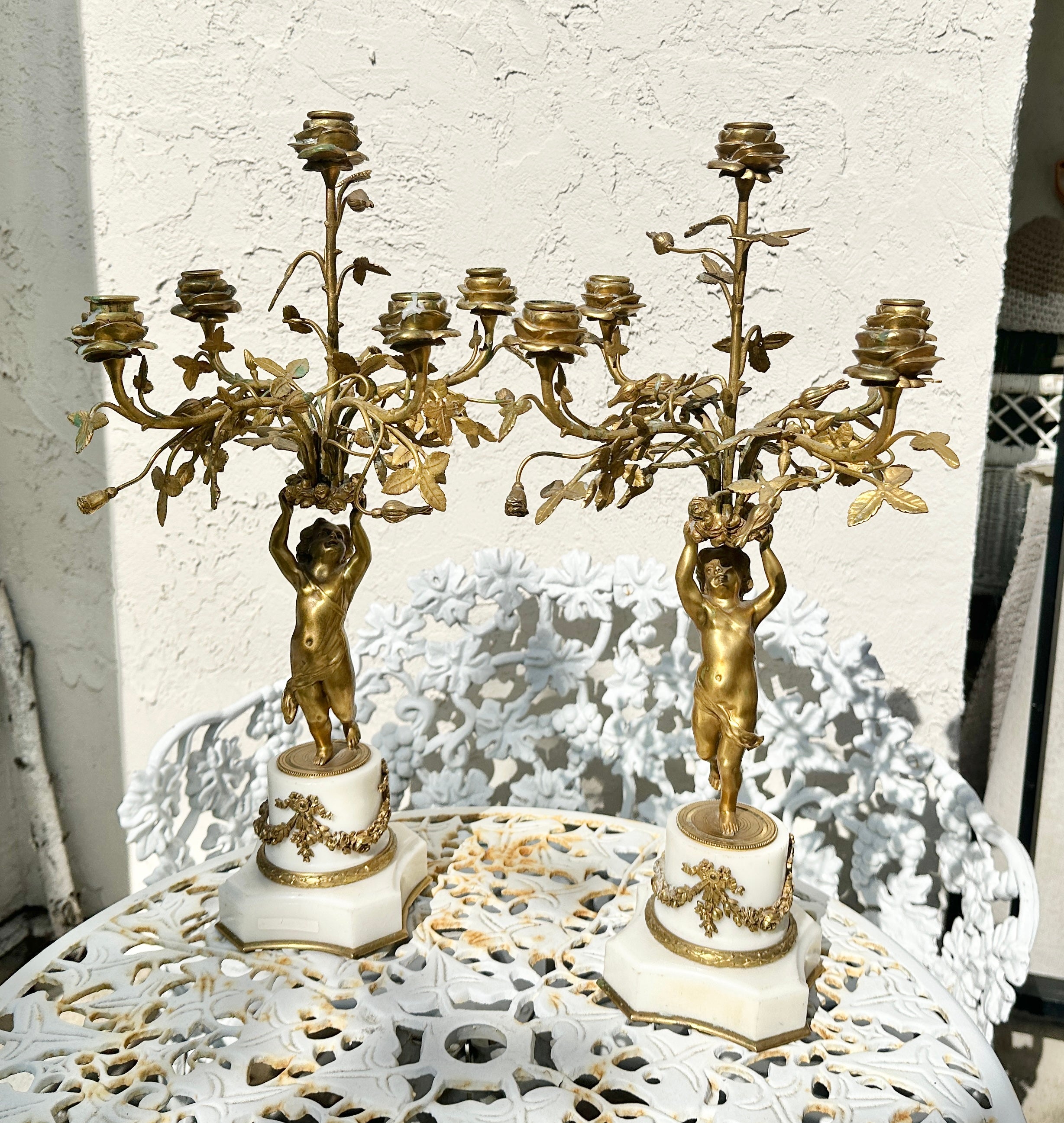 Indulge in an Antique Pair Of French Napoleon III - Belle Epoque Gilt Bronze and White Marble Cherub Putti Candelabras dating to circa 1870.
Elevate your interior with this exquisite pair of 19th Century French gilt bronze candelabras, a magnificent